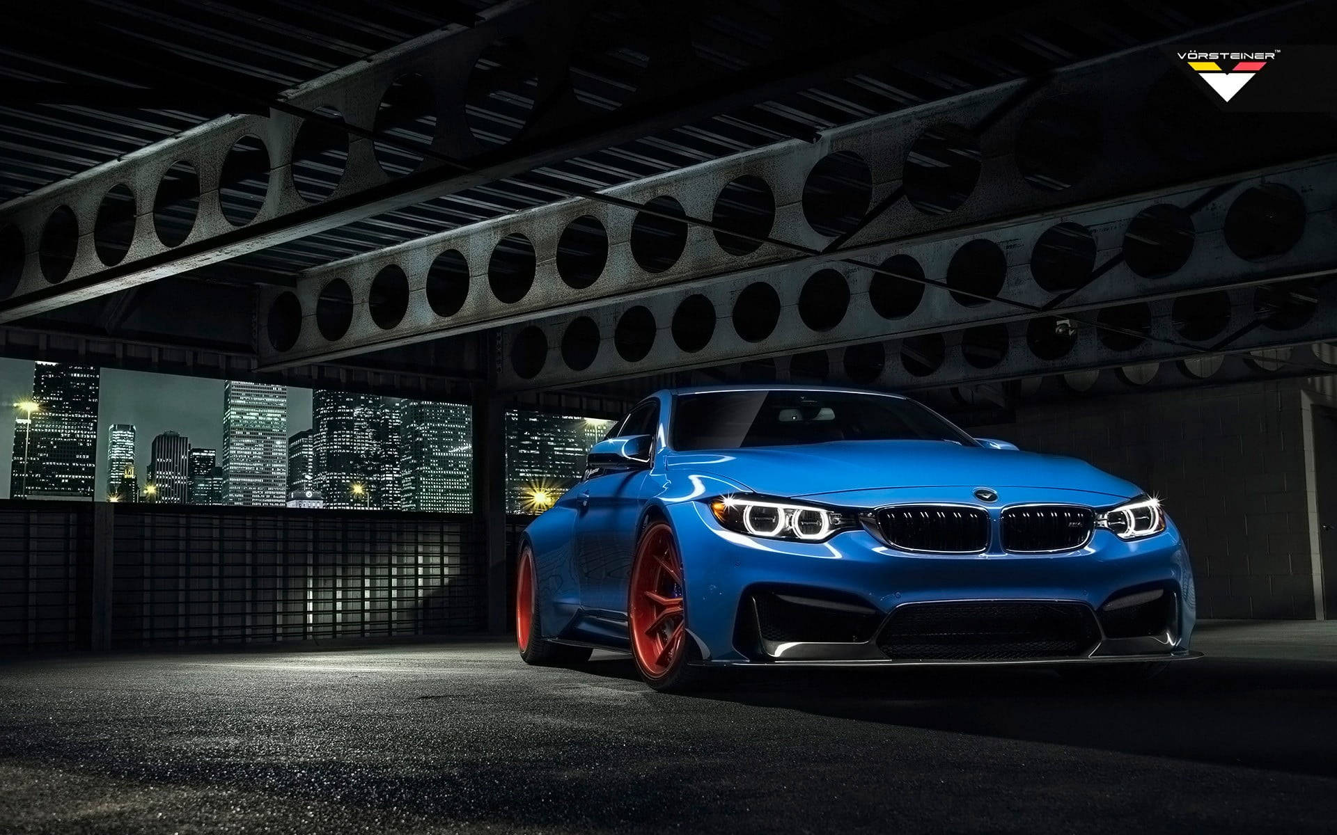 BMW 動圖 桌布 壁紙 — 一輛充滿活力的藍色BMW M4配紅色輪圈，停在鋼橋下，背後是閃爍的城市天際線。