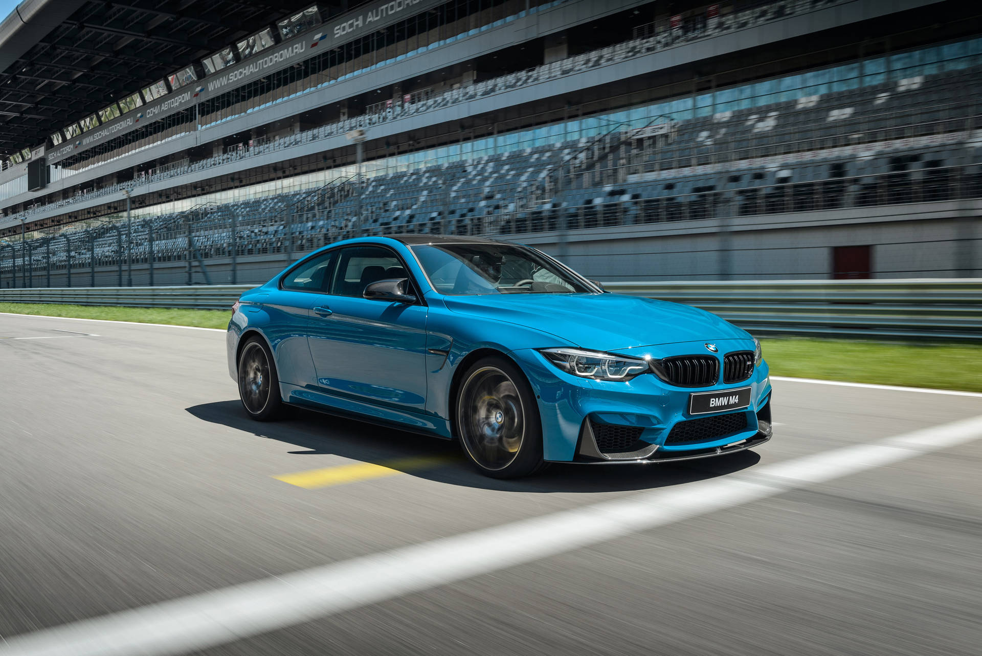 藍色BMW M4在賽道上疾馳，背景有看台。