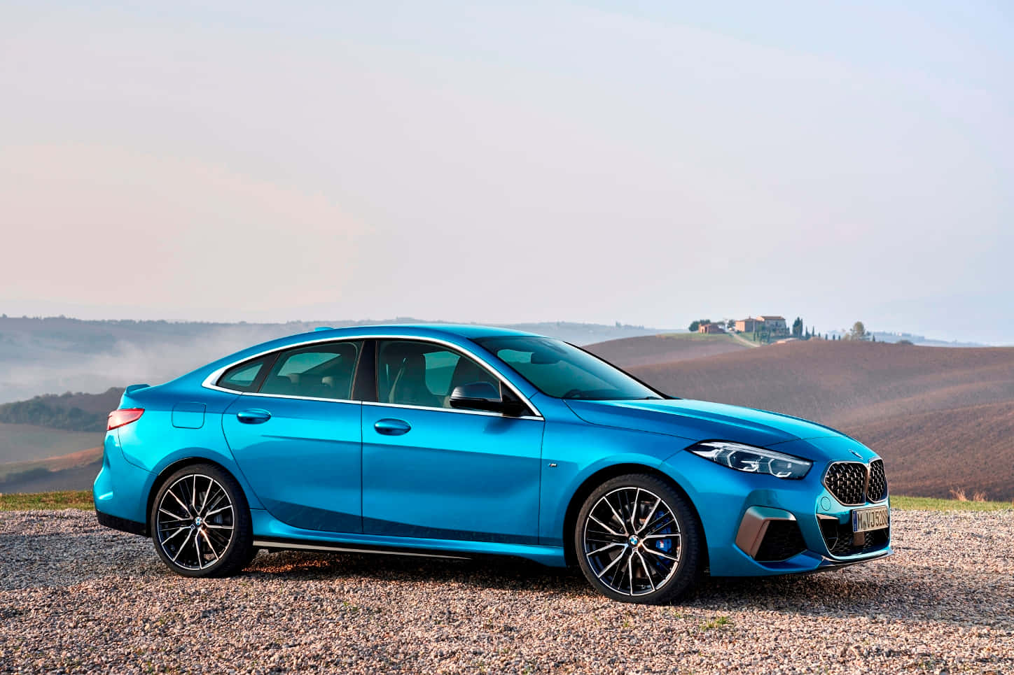Bmw 2 Series 桌布 壁紙 — 一輛充滿活力的藍色BMW轎車停放在碎石山坡上，俯瞰日出時霧氣繚繞的連綿山丘。