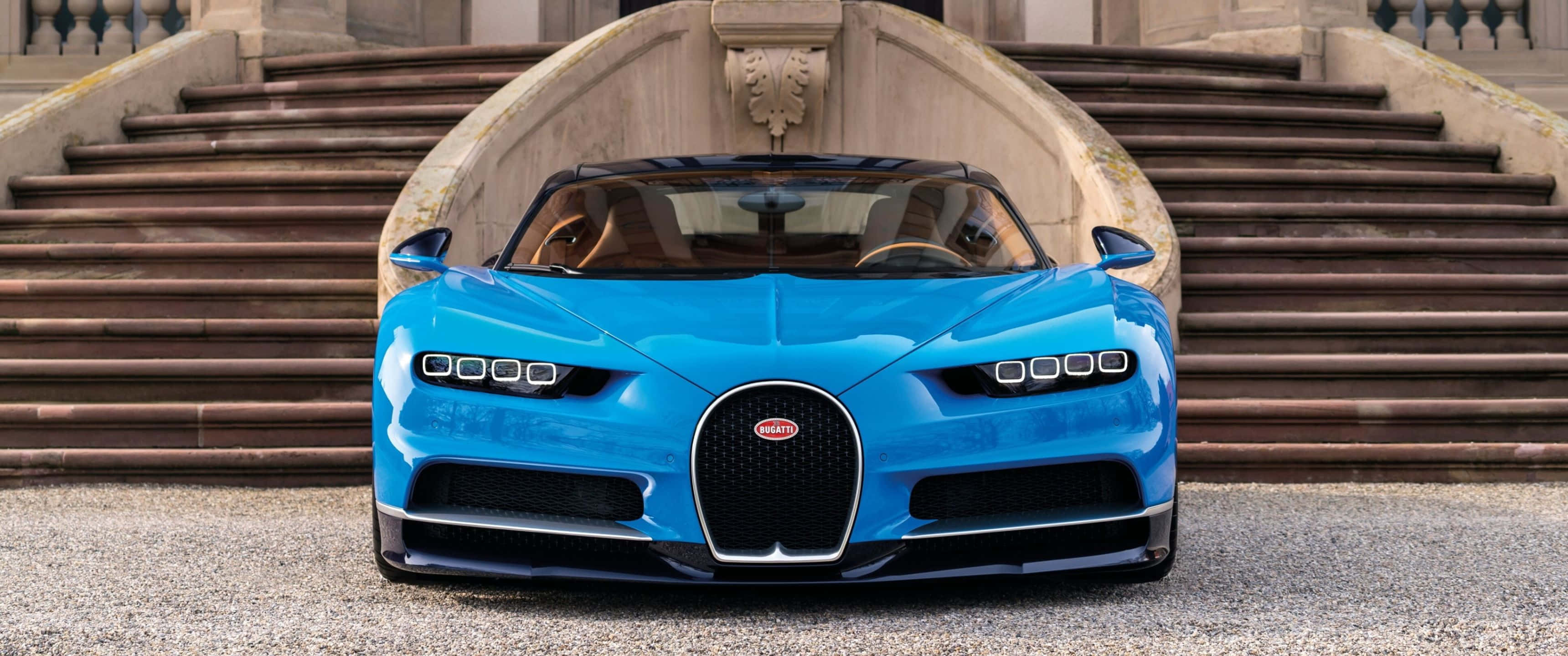 3440x1440p Bugatti 桌布 壁紙 — 一輛充滿活力的藍色Bugatti Chiron在明亮的日光下停在大石階的底部。