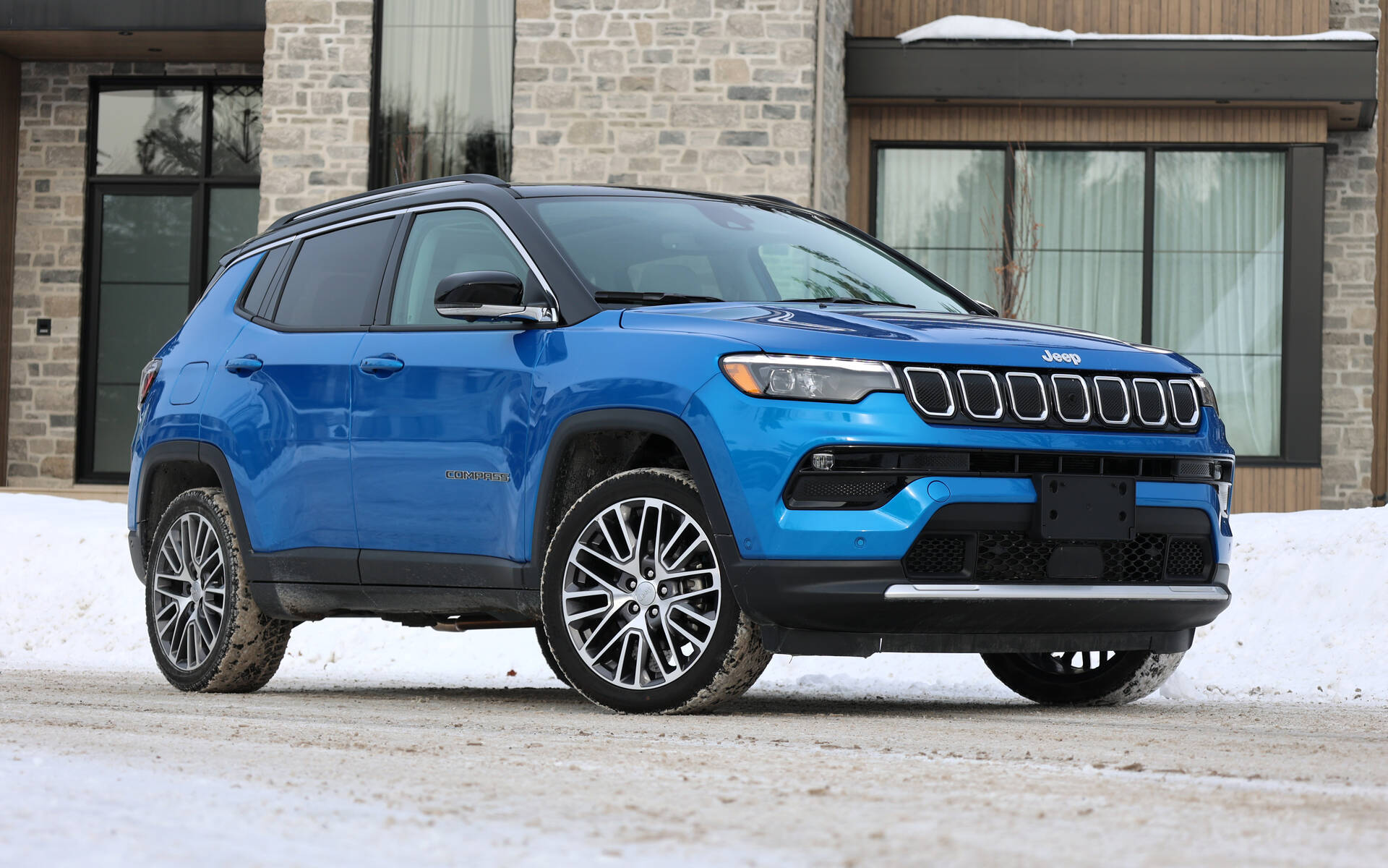雪 桌布 壁紙 — 一輛充滿活力的藍色Jeep Compass SUV停放在雪地上，前方是一座現代石建築。