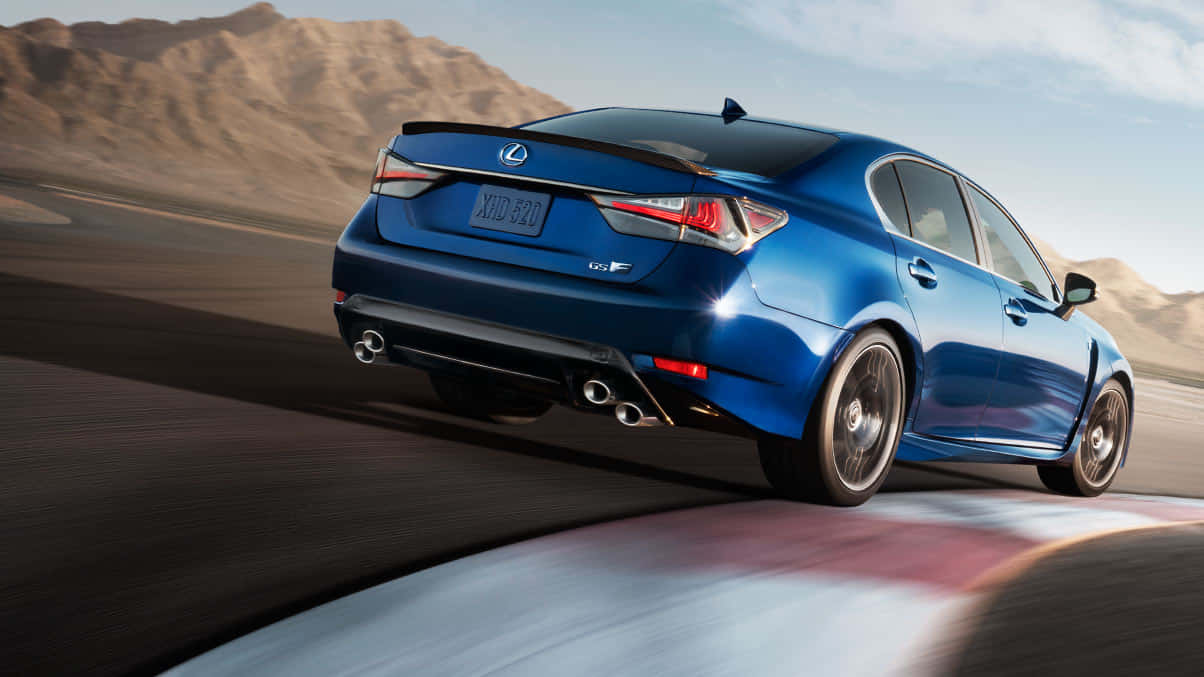 Lexus Gs F 桌布 壁紙 — 一輛充滿活力的藍色Lexus GS-F在沙漠賽道上疾馳，背景是模糊的動感和山區地形。