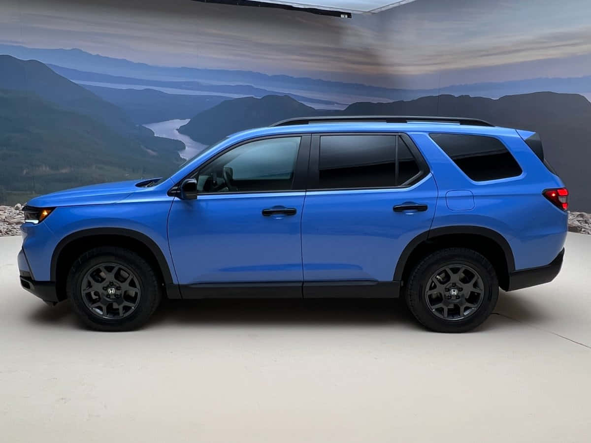 Honda Pilot 桌布 壁紙 — 一輛充滿活力的藍色SUV，帶有黑色飾邊和輪轂，在工作室環境中以山景為背景展示。