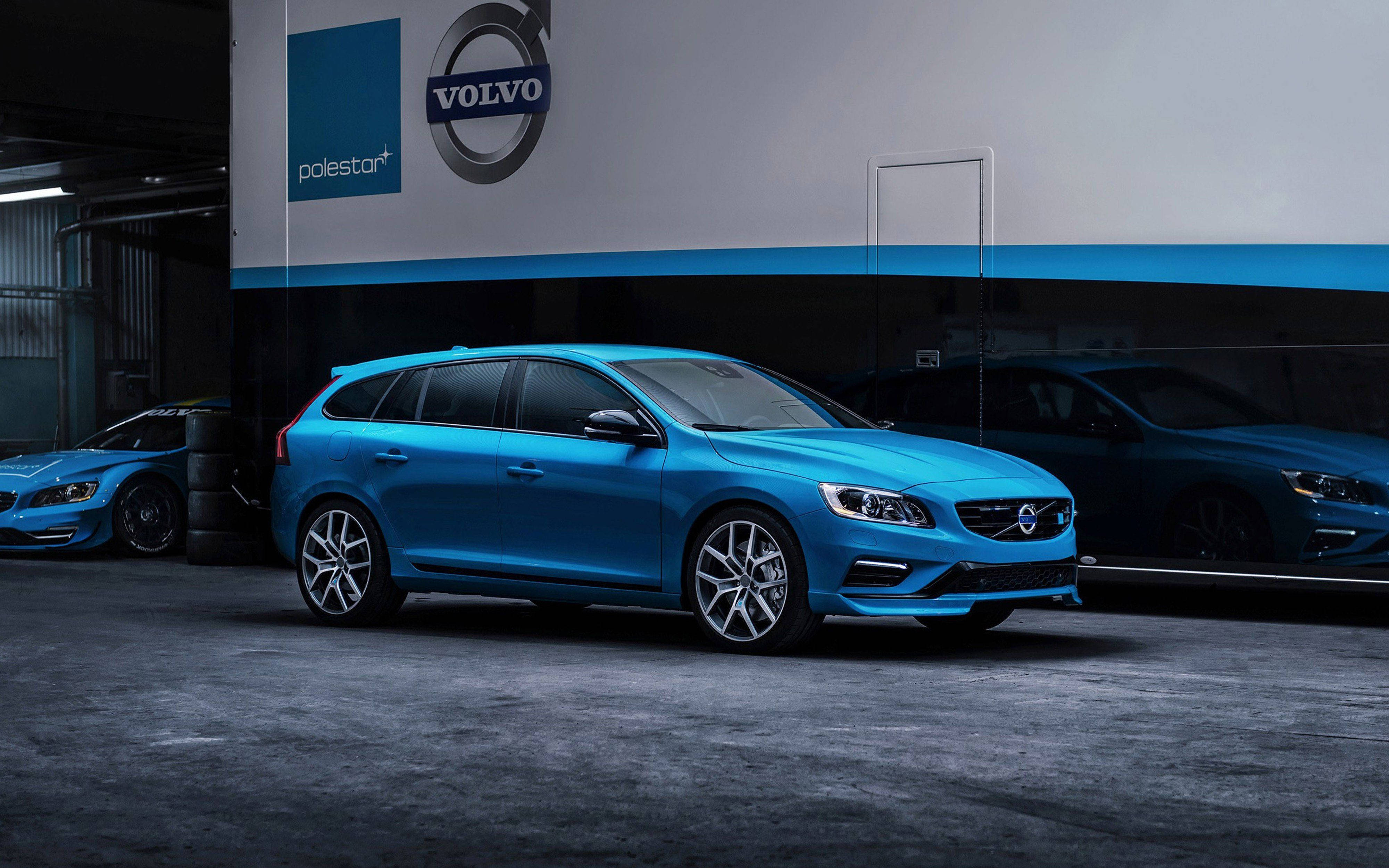 Volvo 桌布 壁紙 — 一輛充滿活力的藍色富豪極星旅行車在工作室燈光下閃閃發光，車庫時尚，牆壁帶有品牌標誌，表面反光。