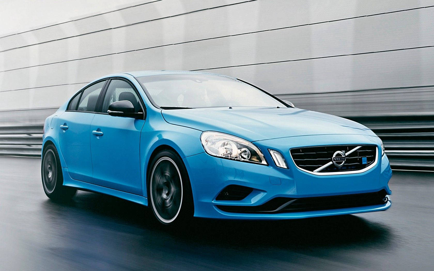 Volvo 桌布 壁紙 — 一輛充滿活力的藍色富豪轎車高速駛過現代金屬牆，動態模糊凸顯其流線型設計。