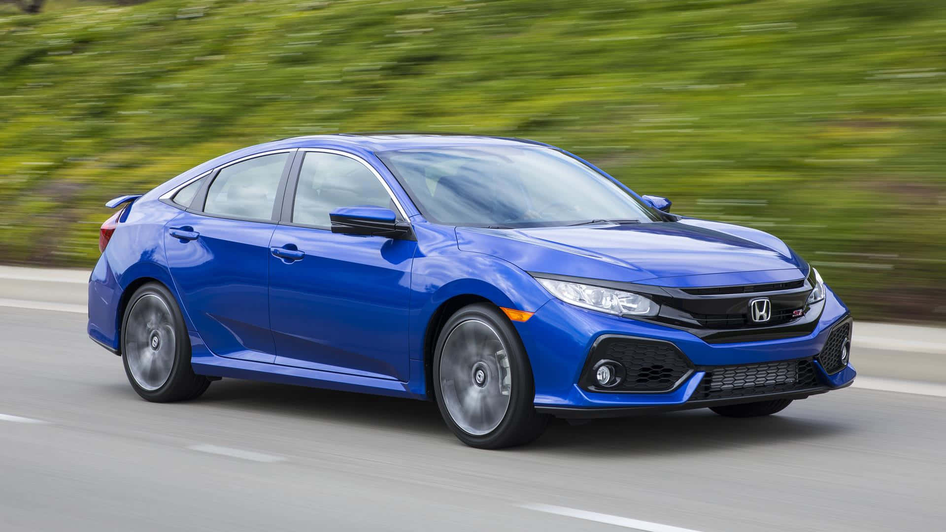 Honda Civic 桌布 壁紙 — 一輛充滿活力的藍色本田思域Si在道路上疾馳，背景是模糊的綠色樹葉。