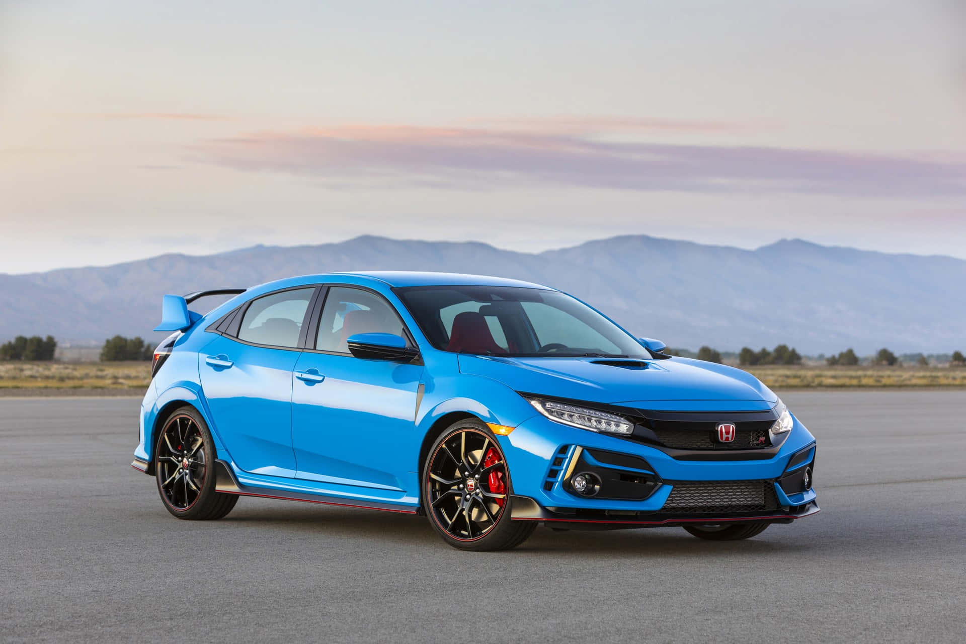 Honda Civic 桌布 壁紙 — 一輛充滿活力的藍色本田思域Type R跑車停在開放的瀝青場地上，遠處山巒在柔和的粉彩天空下。
