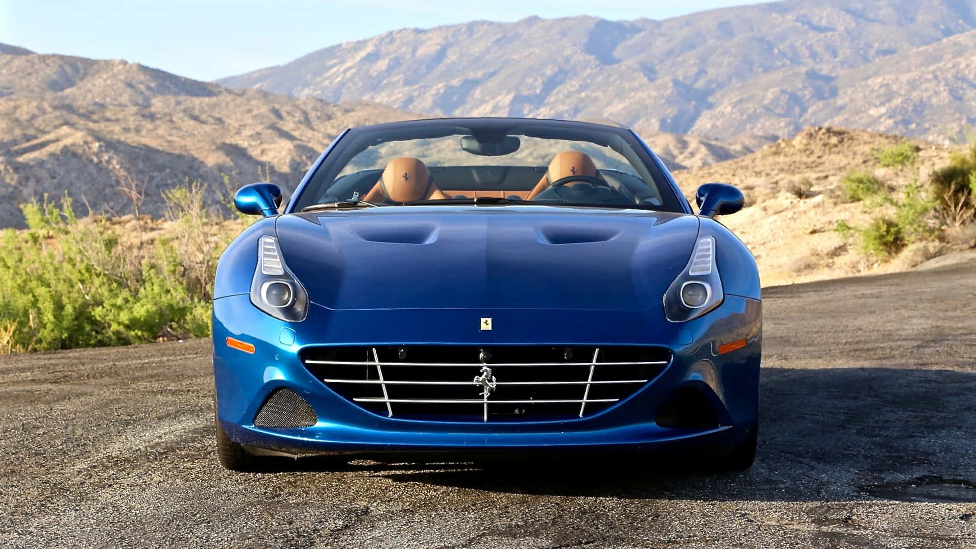 Ferrari California T 桌布 壁紙 — 一輛充滿活力的藍色法拉利加利福尼亞敞篷跑車停在沙漠公路上，背景是崎嶇的山脈。