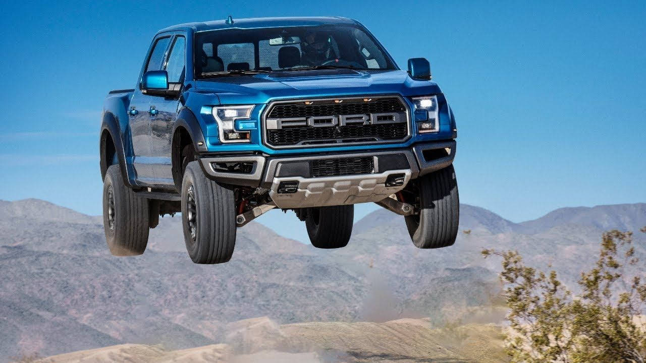 Raptor 桌布 壁紙 — 一輛充滿活力的藍色福特 F-150 Raptor 卡車在沙漠景觀上空飛躍，背景有山脈。