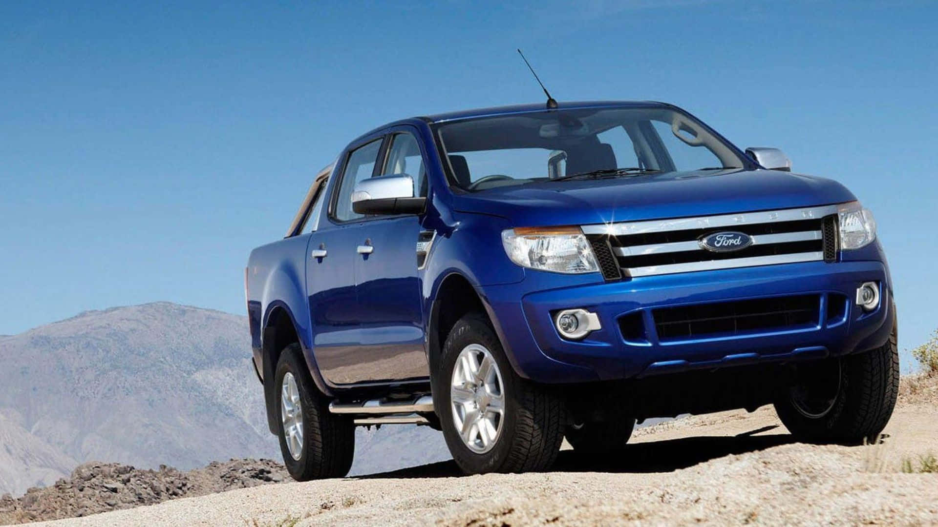 Ford Ranger 桌布 壁紙 — 一輛充滿活力的藍色福特皮卡車停在岩石沙漠小徑上，背景是晴朗的藍天和遠處的山脈。