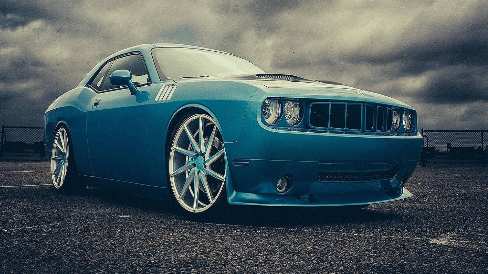 cars 桌布 壁紙 — 一輛充滿活力的藍色肌肉車配備定制輪圈，停放在空地上，上方是戲劇性的暴風雲。