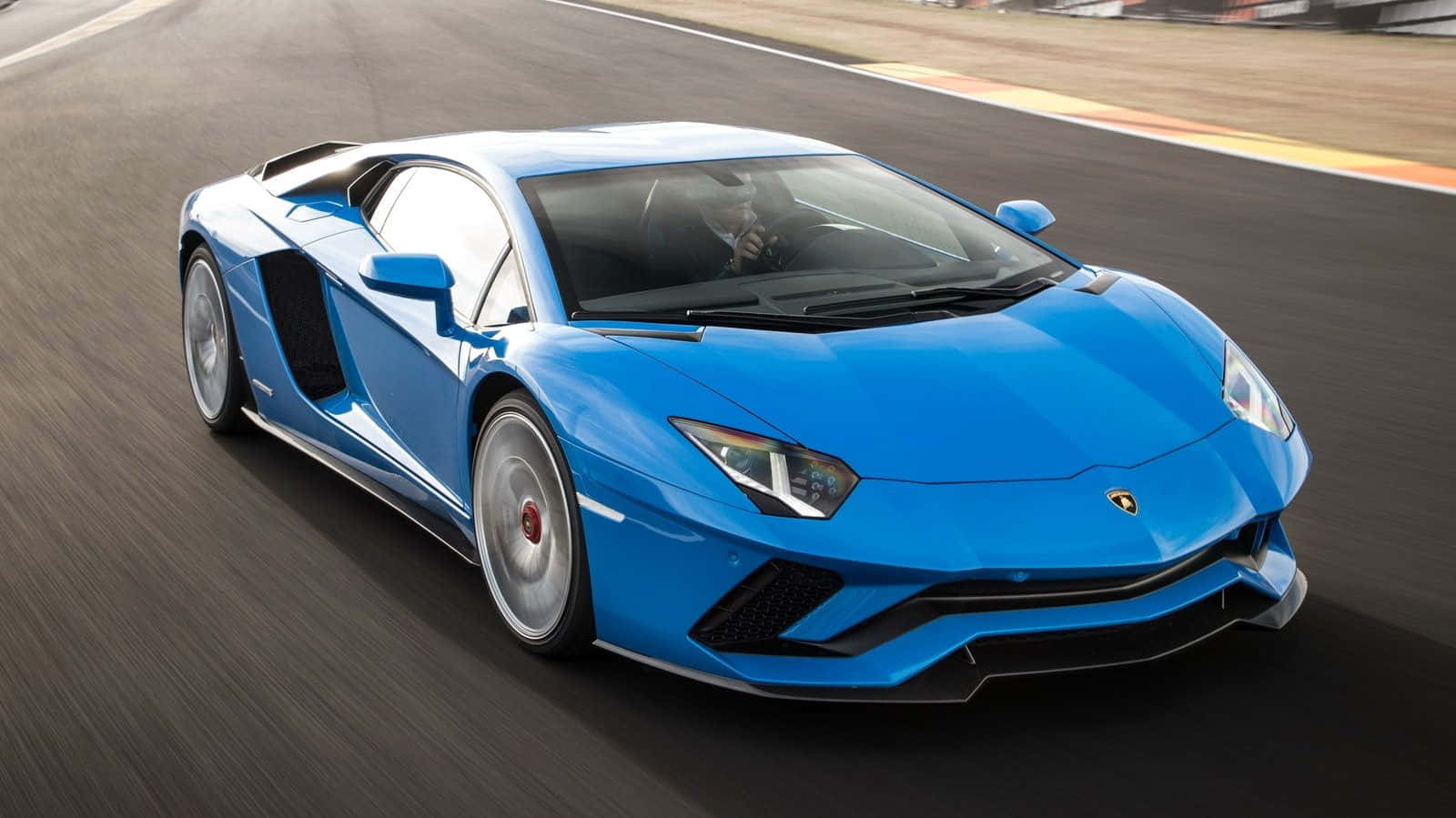 跑車 桌布 壁紙 — 一輛充滿活力的藍色藍寶堅尼Aventador在賽道上疾馳，動態模糊強調其高性能。