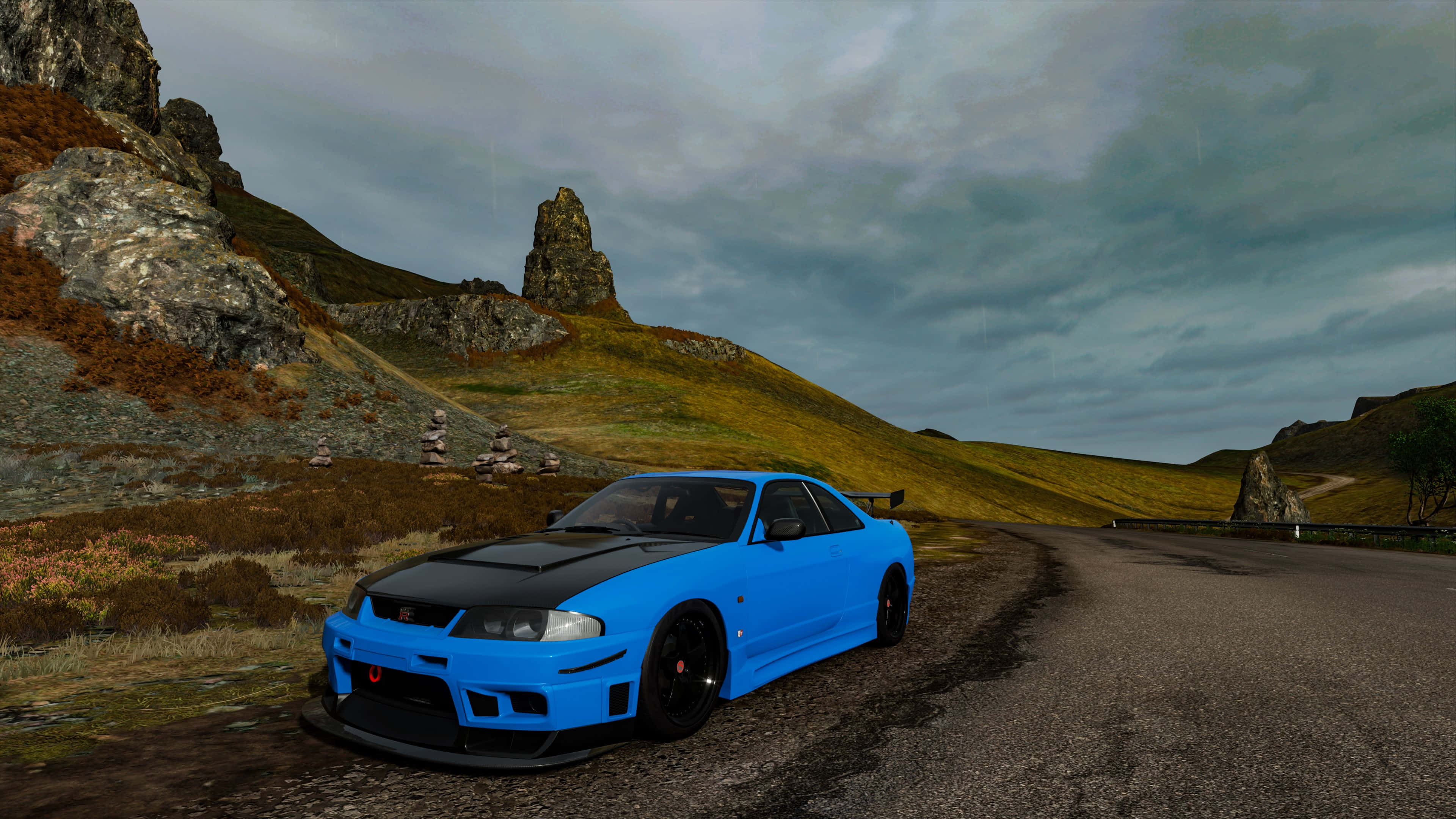 R33 GT-R 桌布 壁紙 — 一輛充滿活力的藍色跑車，帶有黑色點綴，停泊在蜿蜒的山路上，天空多雲。
