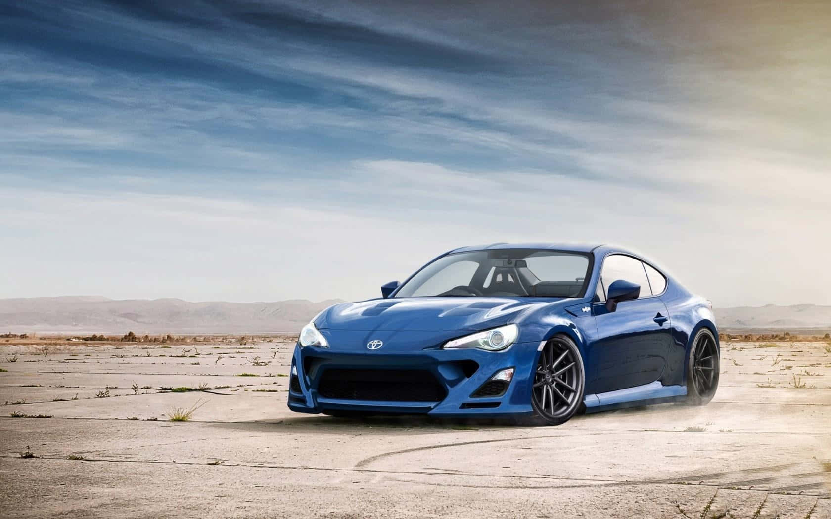 藍色跑車在日落時分於裂開的沙漠路面上飄移。 — Toyota Supra Mk4 壁紙