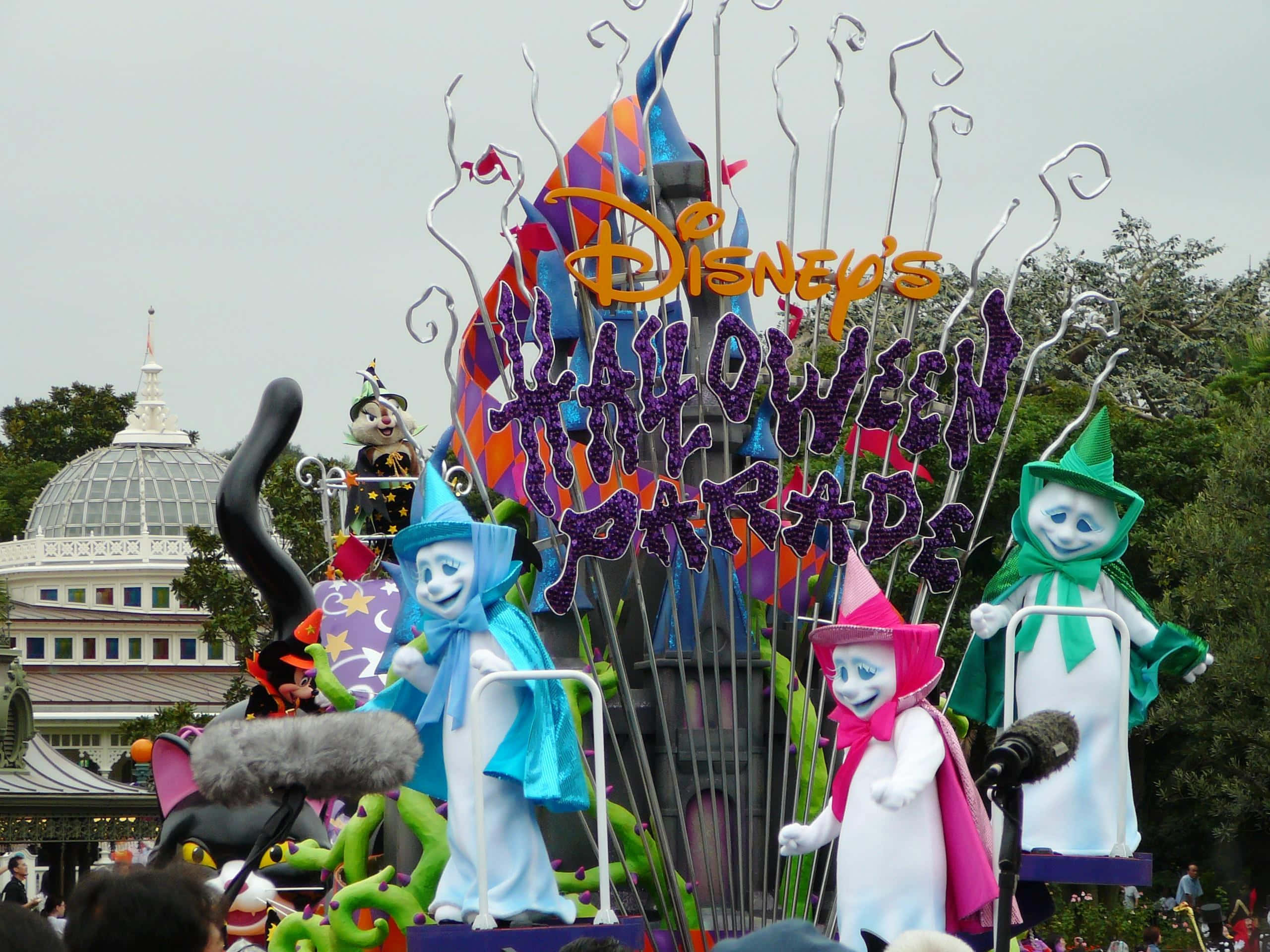 Halloween Parades 桌布 壁紙 — 一輛充滿活力的迪士尼萬聖節遊行花車，以多雲的天空為背景，展示色彩繽紛的女巫角色和恐怖裝飾。