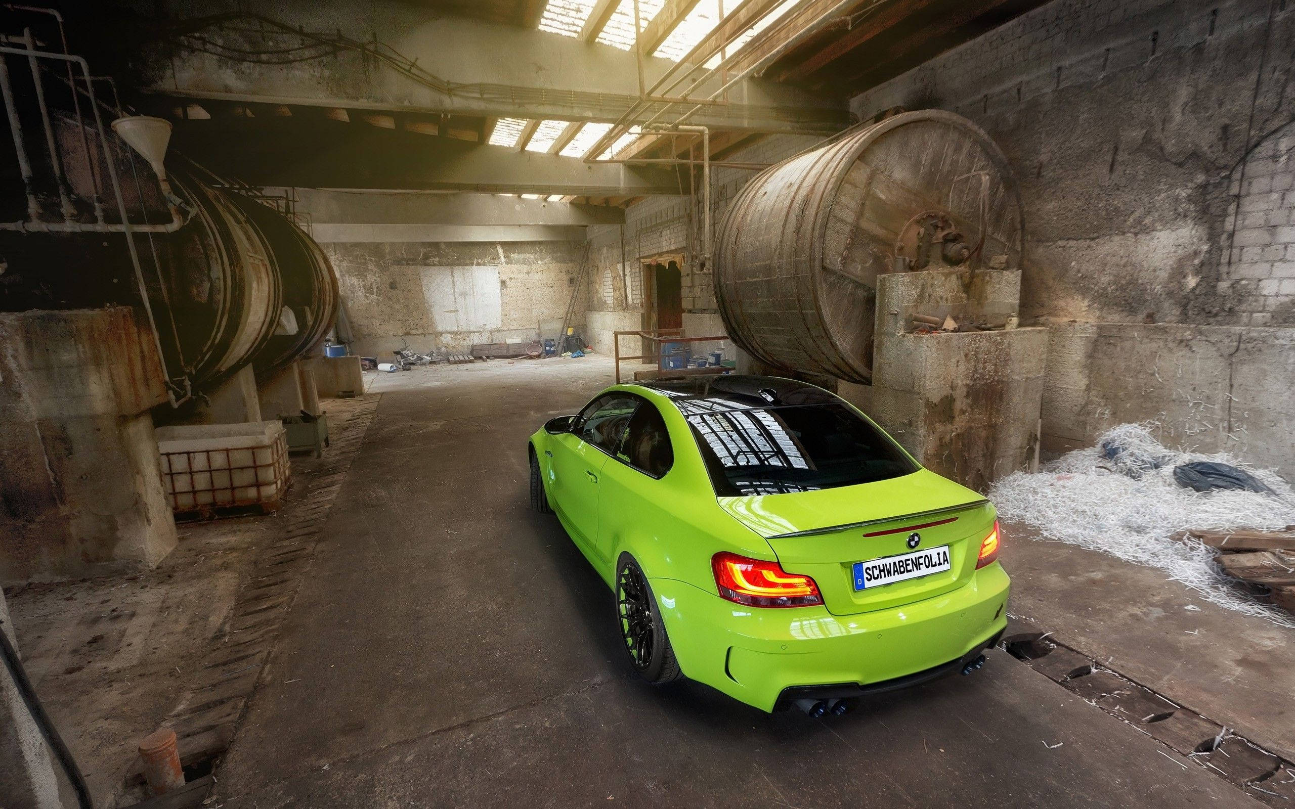 m 桌布 壁紙 — 一輛充滿活力的青檸綠色BMW M2雙門跑車停放在一個粗糙的工業倉庫中，內有大型生鏽儲罐和天窗照明。