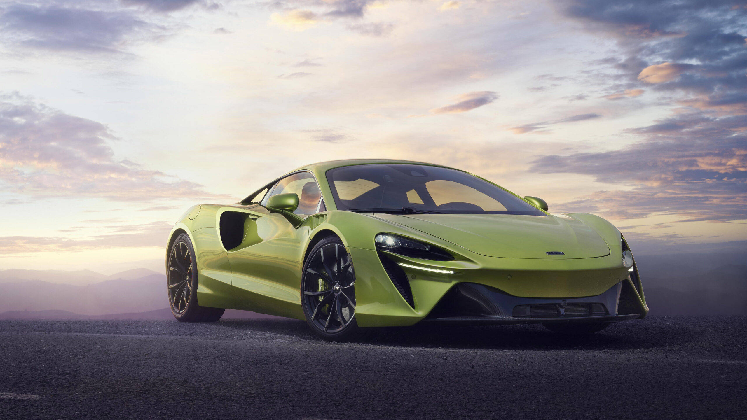 跑車 桌布 壁紙 — 一輛充滿活力的青檸綠色McLaren跑車在柔和的日落天空下閃閃發光，背景是遠處的山脈。