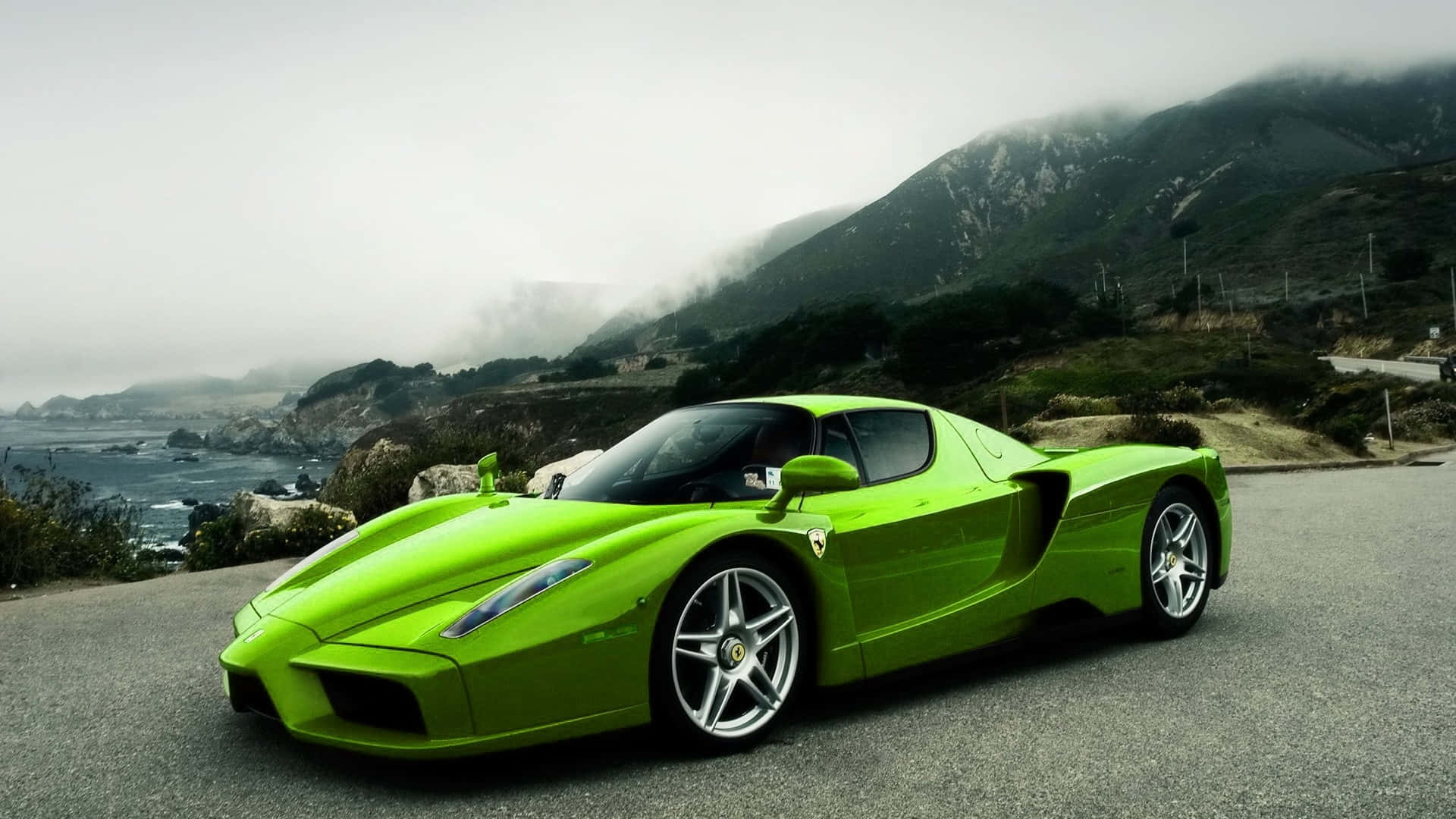 Ferrari Enzo 桌布 壁紙 — 一輛充滿活力的青檸綠色法拉利Enzo停泊在沿海公路上，背景是霧氣繚繞的山脈和海洋。