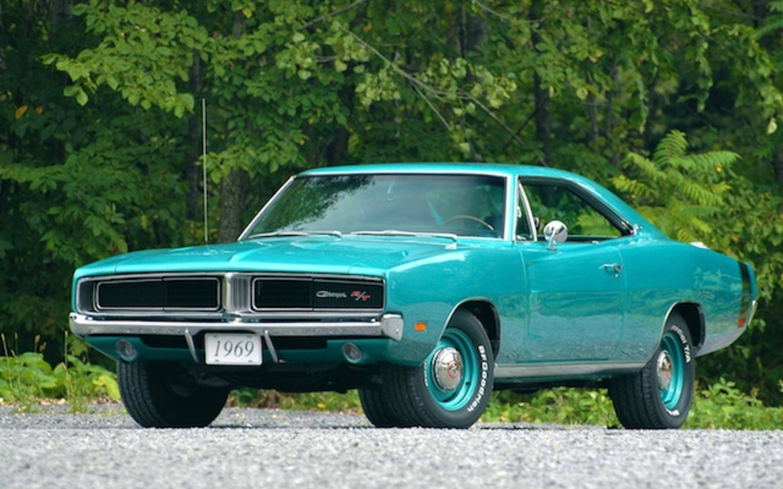 Charger 桌布 壁紙 — 一輛充滿活力的青綠色1969年道奇Charger經典肌肉車停在碎石上，背景是茂密的綠樹。