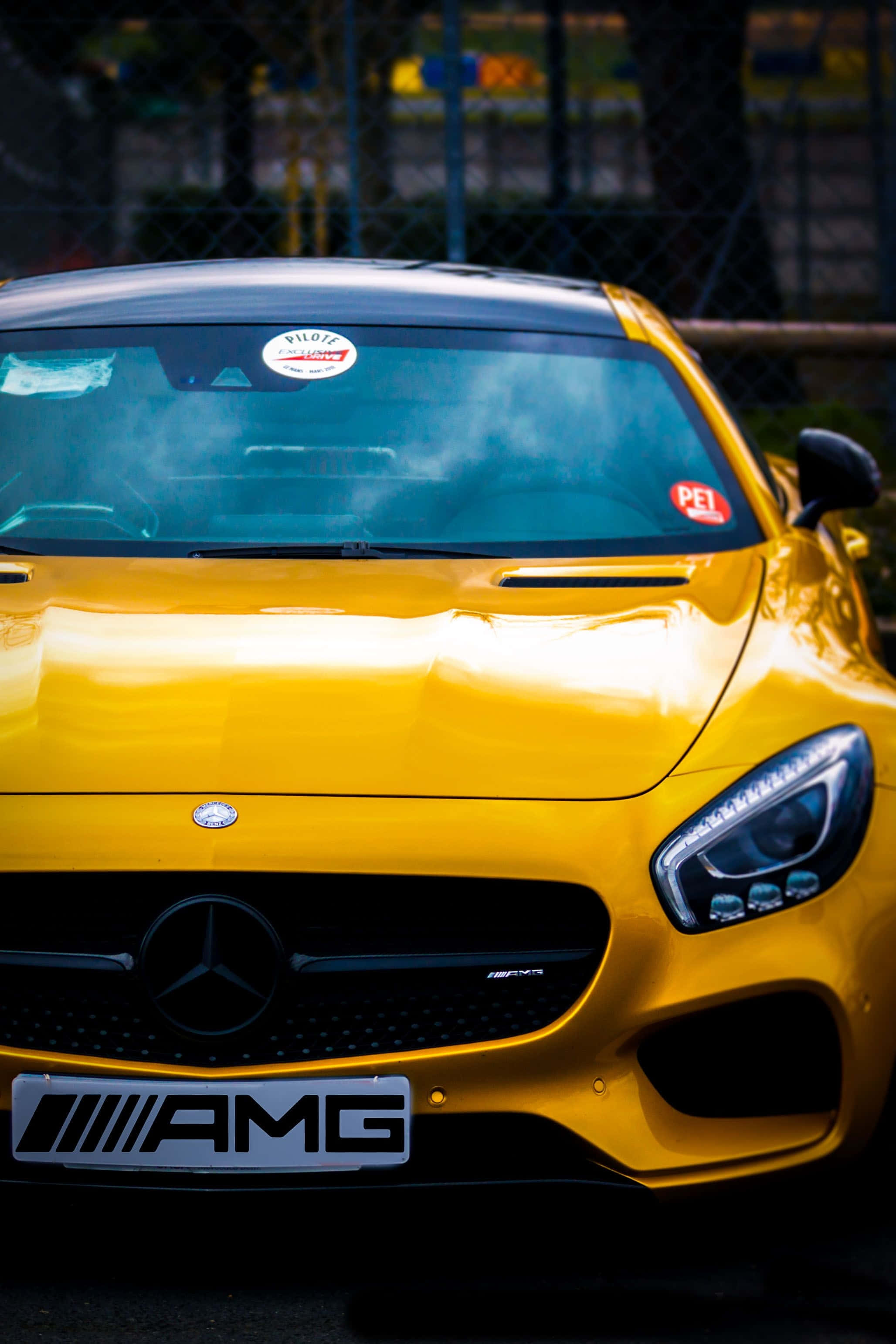 Mercedes 桌布 壁紙 — 一輛充滿活力的黃色 Mercedes-AMG 跑車在明亮的陽光下閃耀，呈現專注的前視圖。