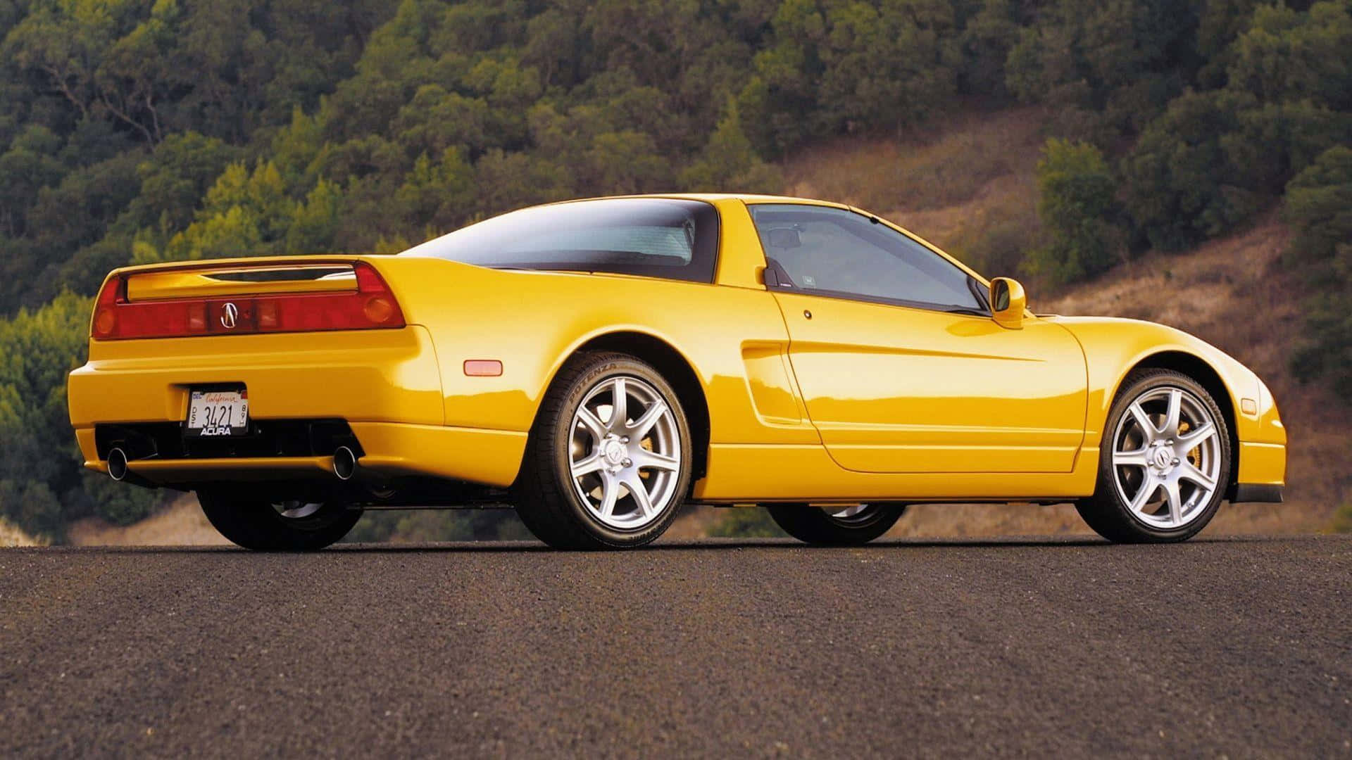 Acura Nsx 桌布 壁紙 — 一輛充滿活力的黃色Acura NSX跑車停泊在瀝青路上，背景是樹木繁茂的山坡。