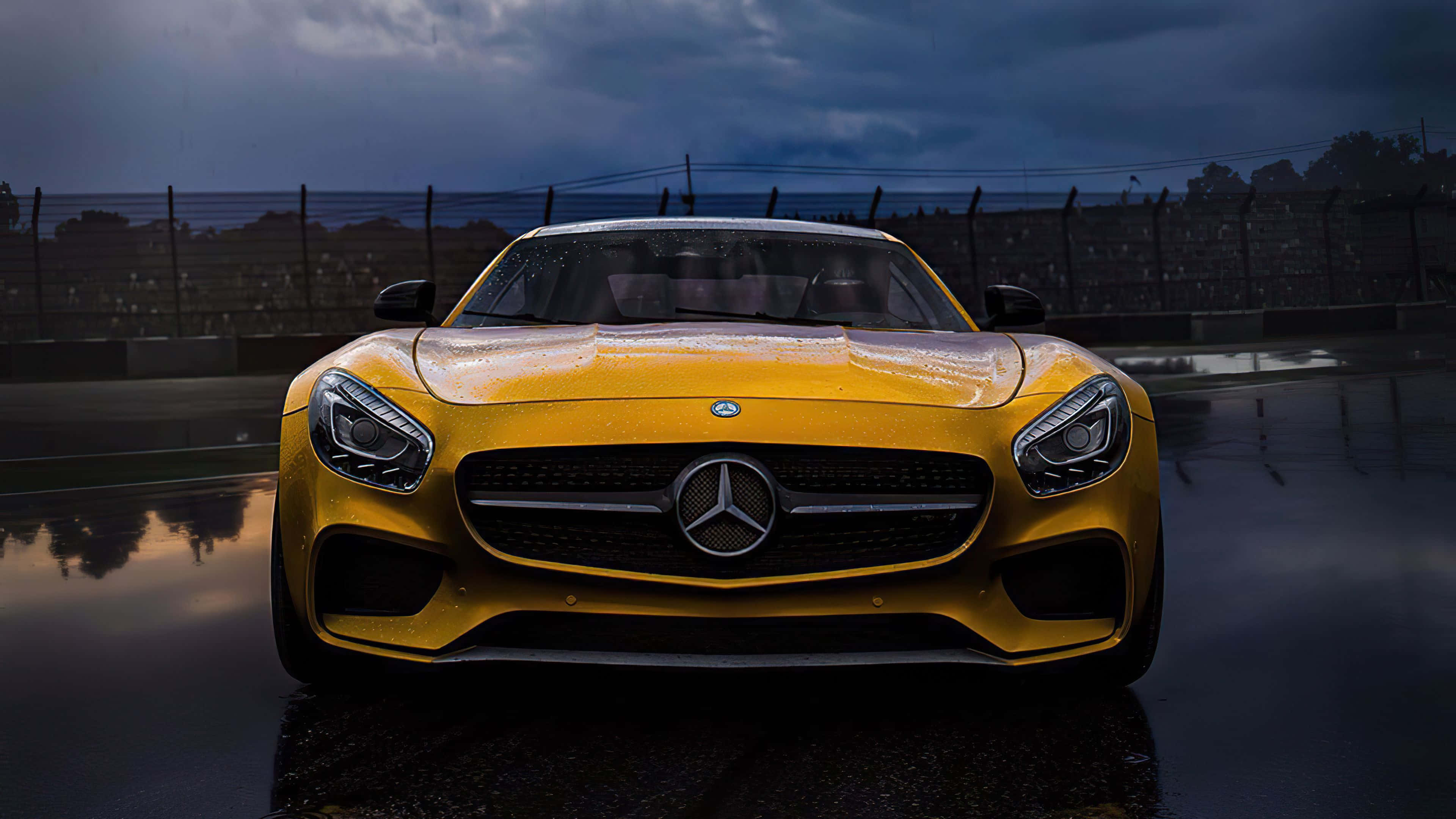 Mercedes Amg 桌布 壁紙 — 一輛充滿活力的黃色Mercedes-AMG GT停放在濕滑的賽車場上，背景是暴風雨的天空，帶有戲劇性的倒影。