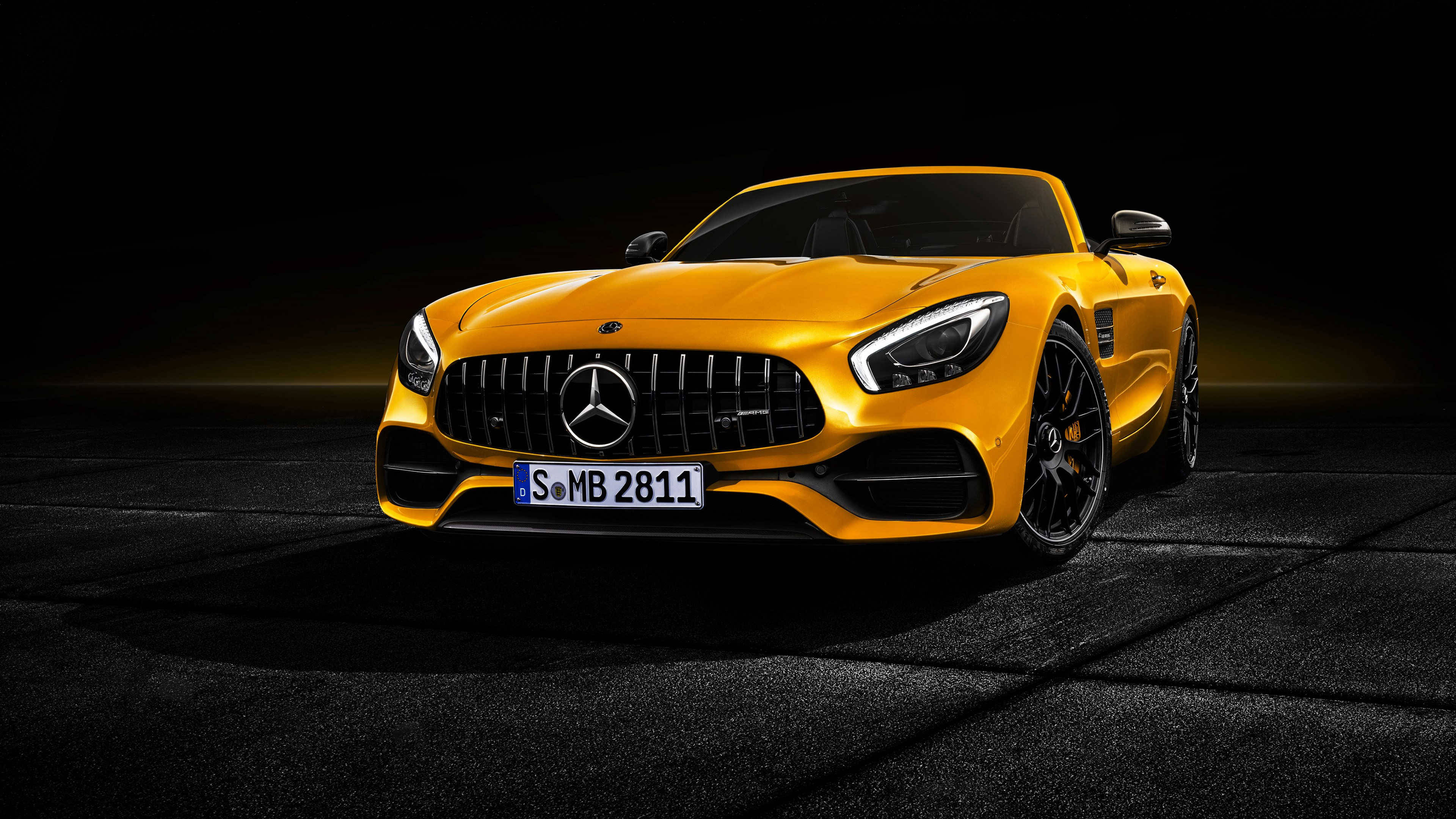 4K 奔馳壁紙 桌布 壁紙 — 一輛充滿活力的黃色Mercedes-AMG GT Roadster在戲劇性的工作室燈光下，在黑色瀝青背景上閃閃發光。