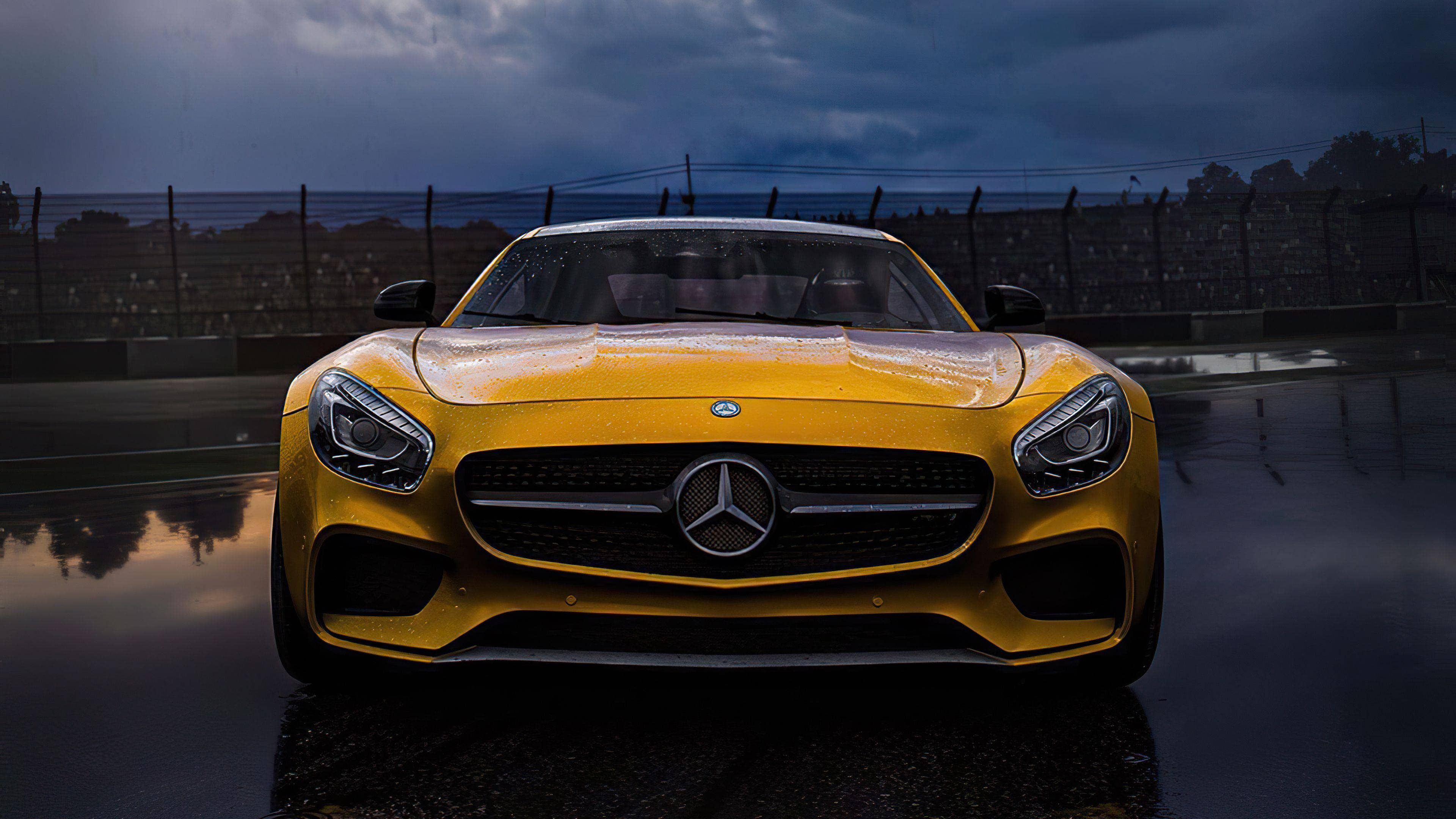 4K 奔馳壁紙 桌布 壁紙 — 一輛充滿活力的黃色Mercedes-AMG GT跑車在暴風雨的天空下，在潮濕的賽道上閃閃發光。
