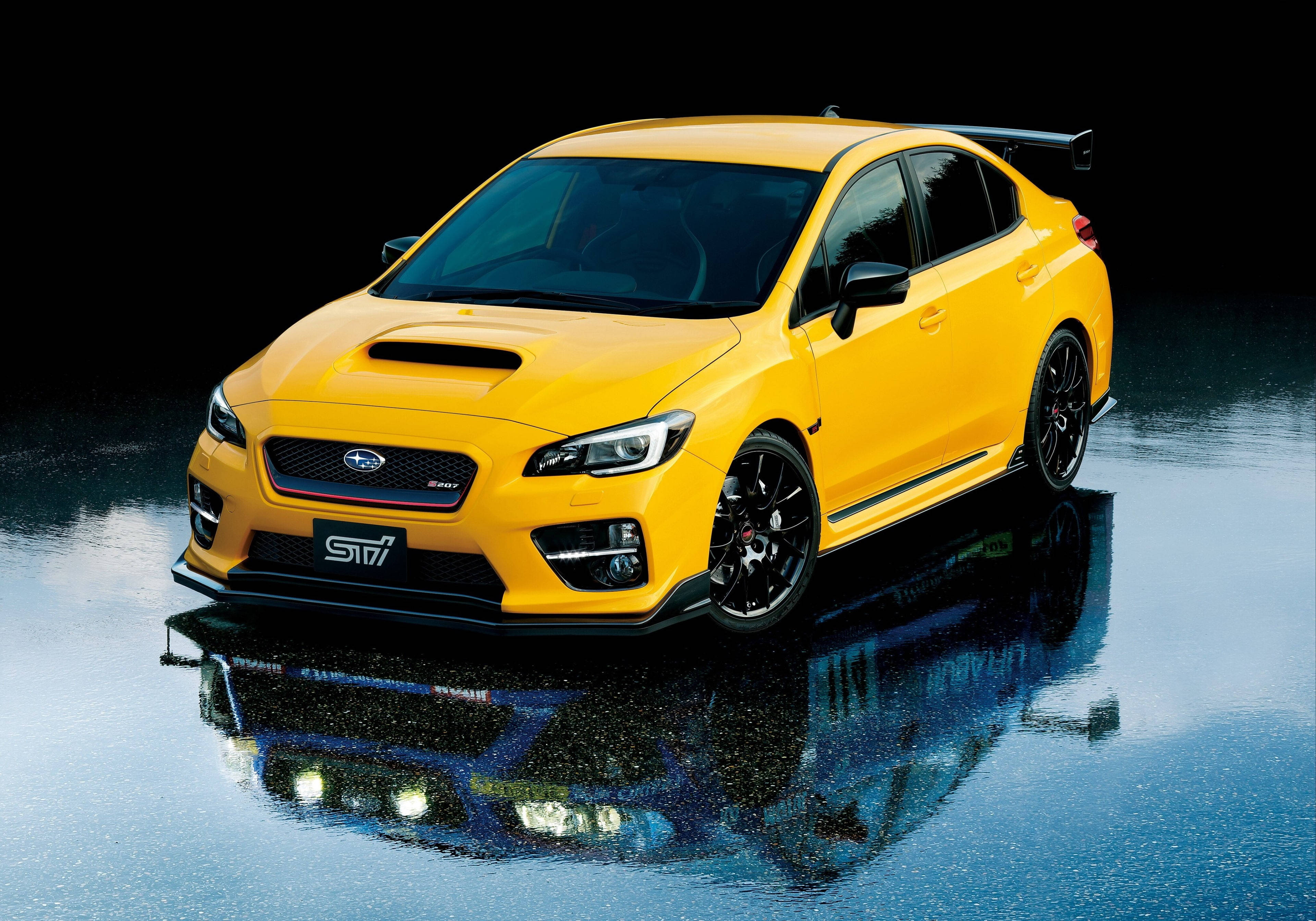 跑車 桌布 壁紙 — 一輛充滿活力的黃色Subaru WRX STI轎車在攝影棚燈光下，於潮濕的反光表面上閃閃發光。