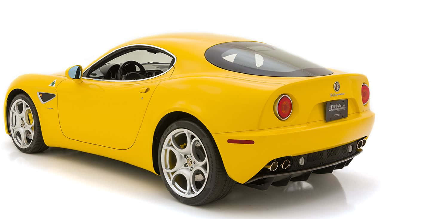 Alfa Romeo 8c Competizione 桌布 壁紙 — 一輛充滿活力的黃色愛快羅密歐8C Competizione跑車，以工作室拍攝方式從後方四分之三角度展示。