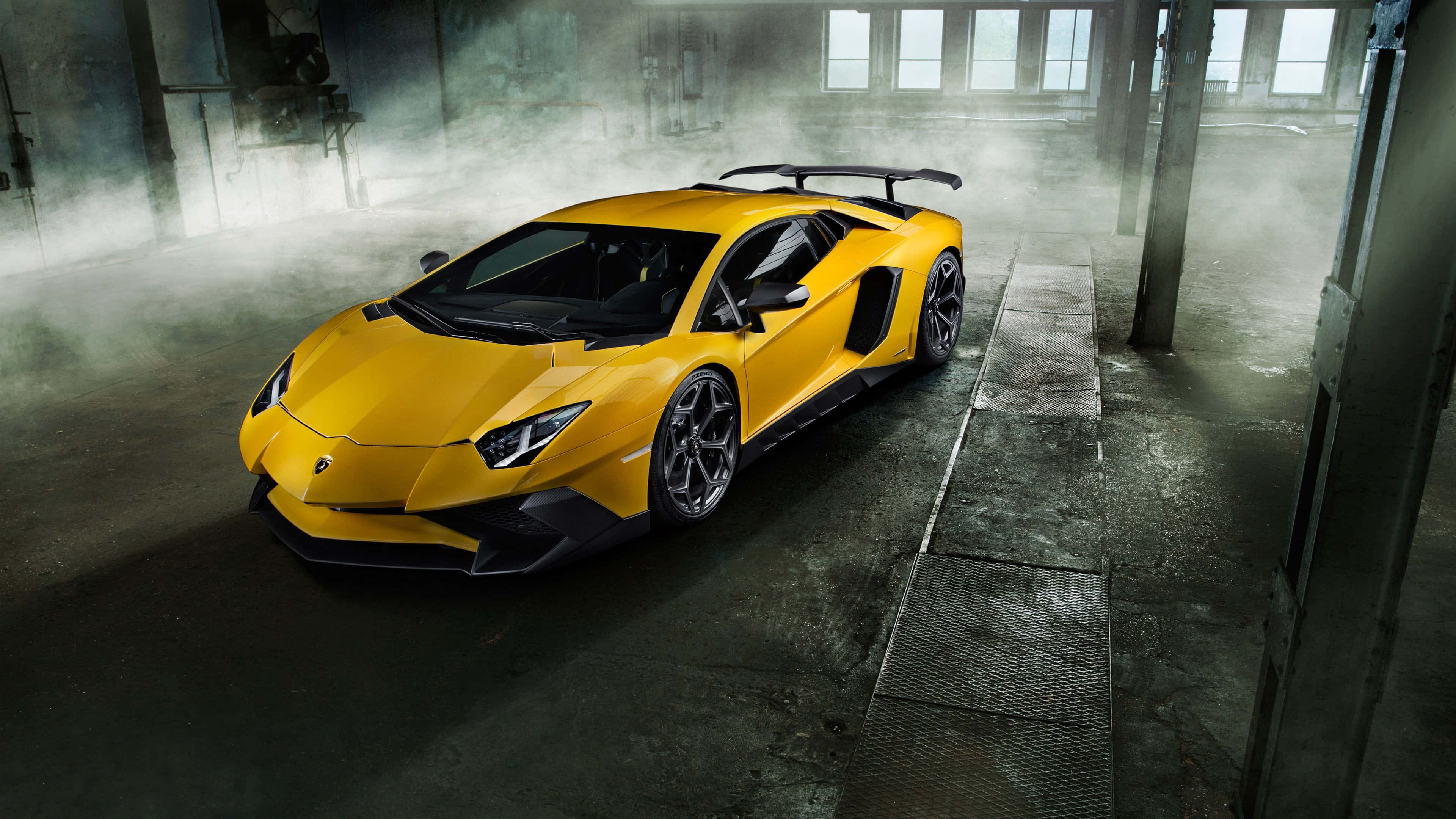 極高畫質 桌布 壁紙 — 一輛充滿活力的黃色藍寶堅尼 Aventador SVJ 在煙霧瀰漫的工業倉庫中，在戲劇性的燈光下閃閃發光。