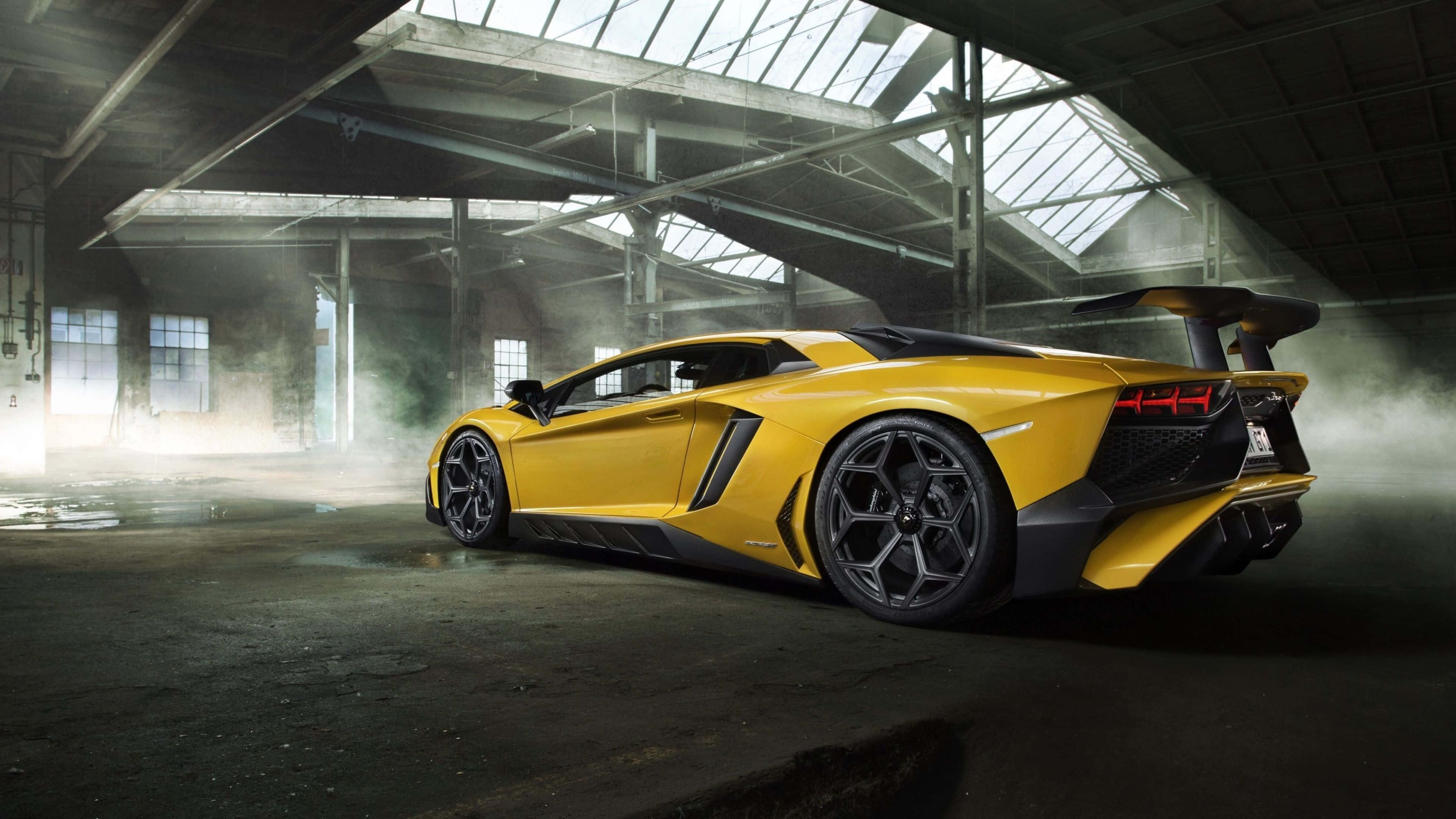 4K 藍寶堅尼 桌布 壁紙 — 一輛充滿活力的黃色藍寶堅尼 Aventador SVJ 在工業天窗下，於煙霧瀰漫的廢棄倉庫中閃閃發光。