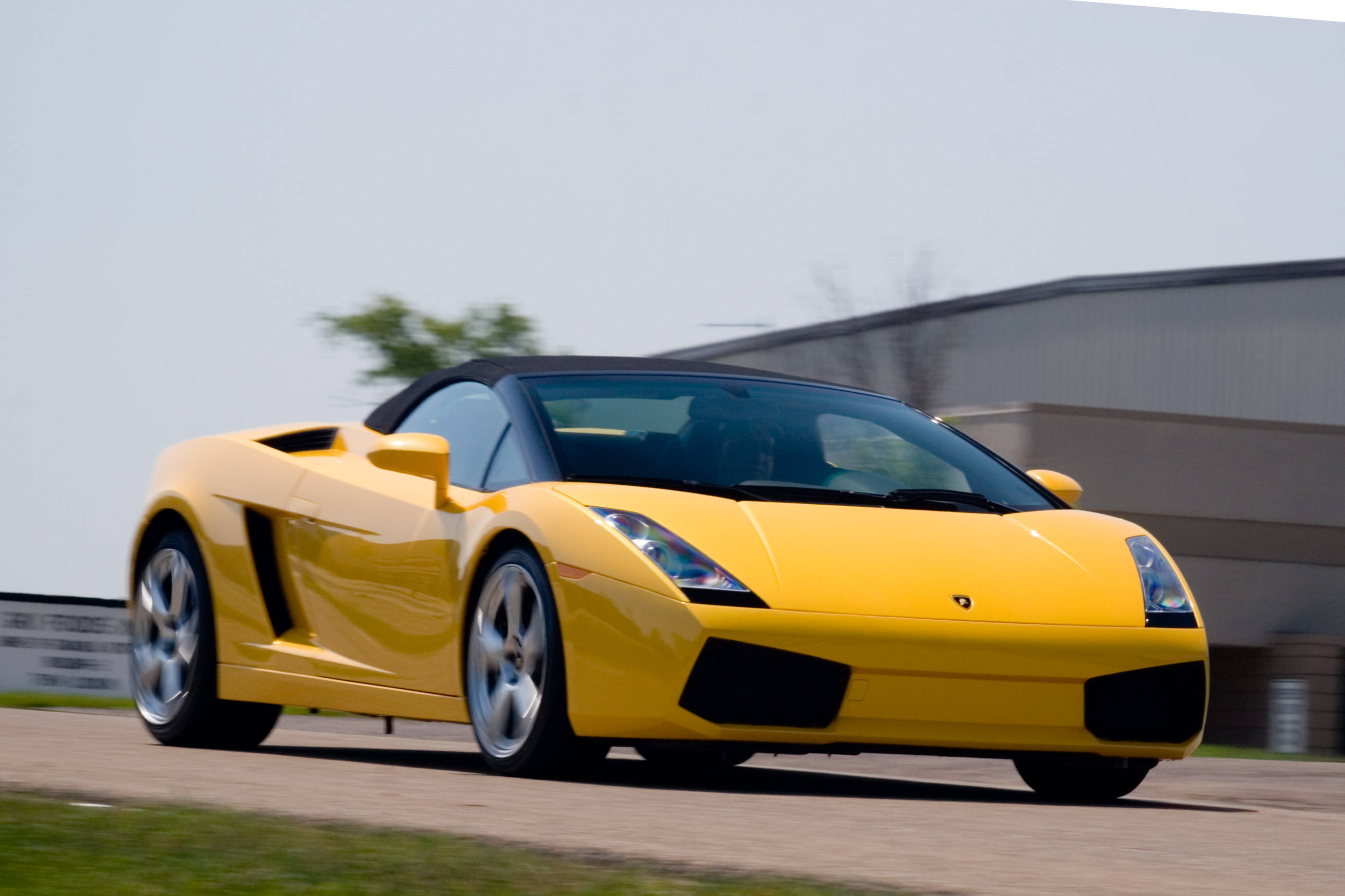 4K 藍寶堅尼 桌布 壁紙 — 一輛充滿活力的黃色藍寶堅尼 Gallardo Spyder 在賽道上疾馳，背景呈現動態模糊效果。