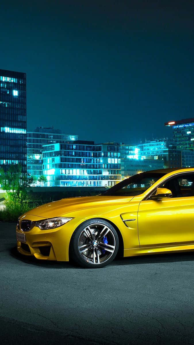BMW 動圖 桌布 壁紙 — 一輛充滿活力的黃色跑車在夜晚的城市燈光下，以燈火通明的摩天大樓為背景閃閃發光。