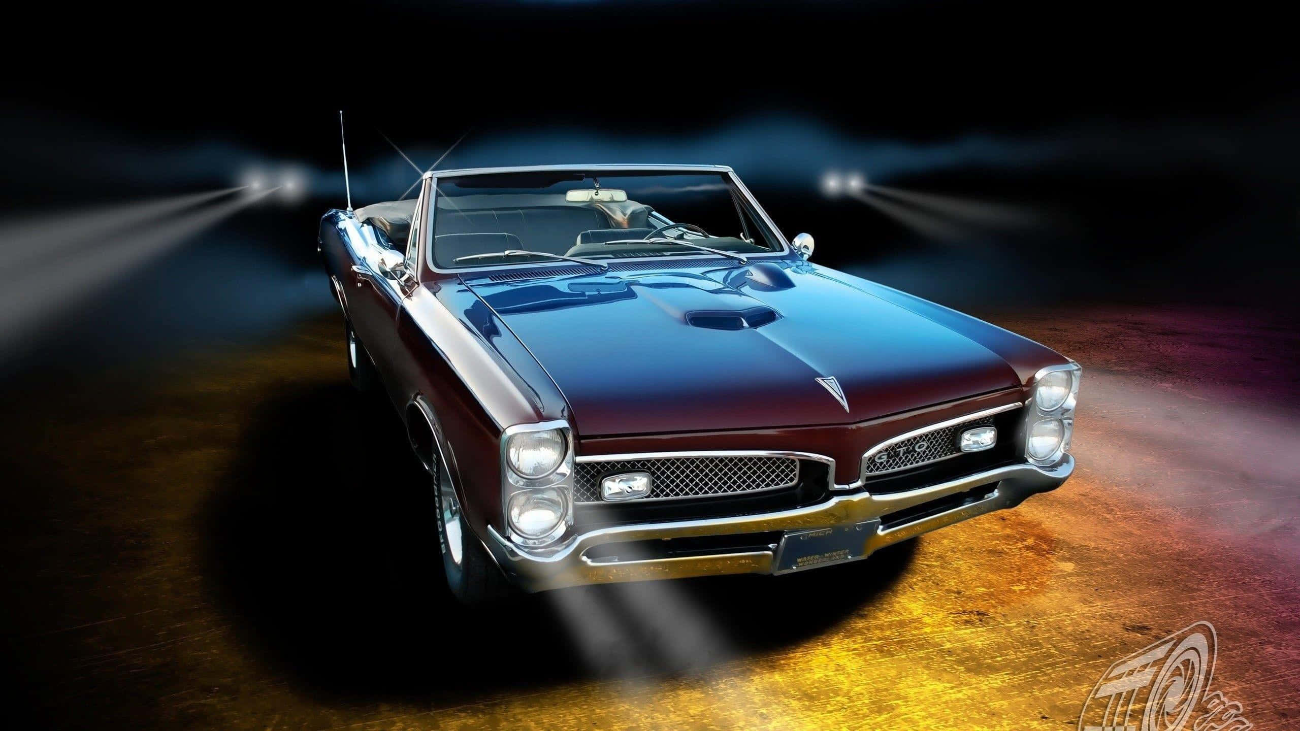 Pontiac 桌布 壁紙 — 一輛光亮的栗色經典敞篷肌肉車在黑暗舞台上戲劇性的聚光燈下閃耀，帶有火橙色地板反射。