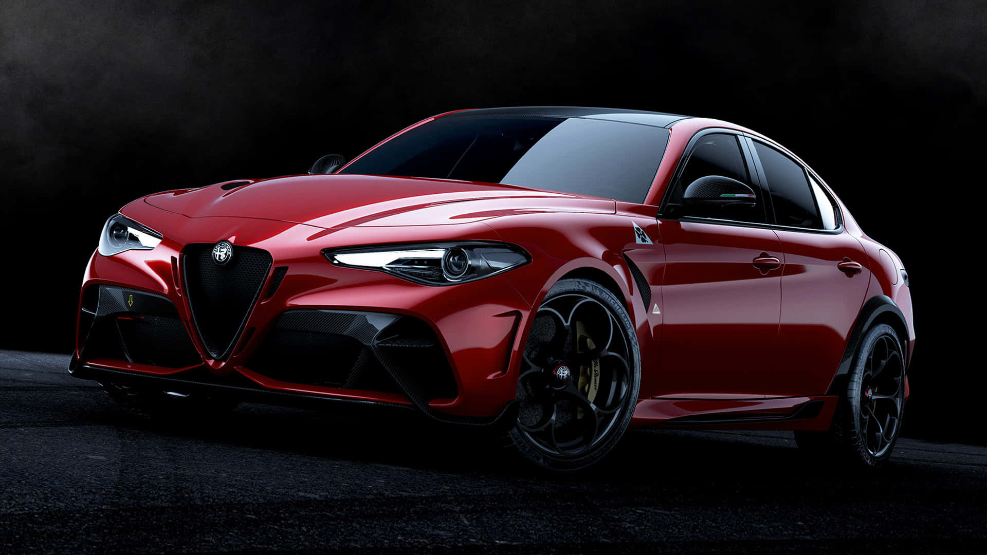 愛快羅密歐 桌布 壁紙 — 一輛光亮的紅色 Alfa Romeo 運動轎車在戲劇性的工作室燈光下，在黑暗煙霧背景中閃耀。