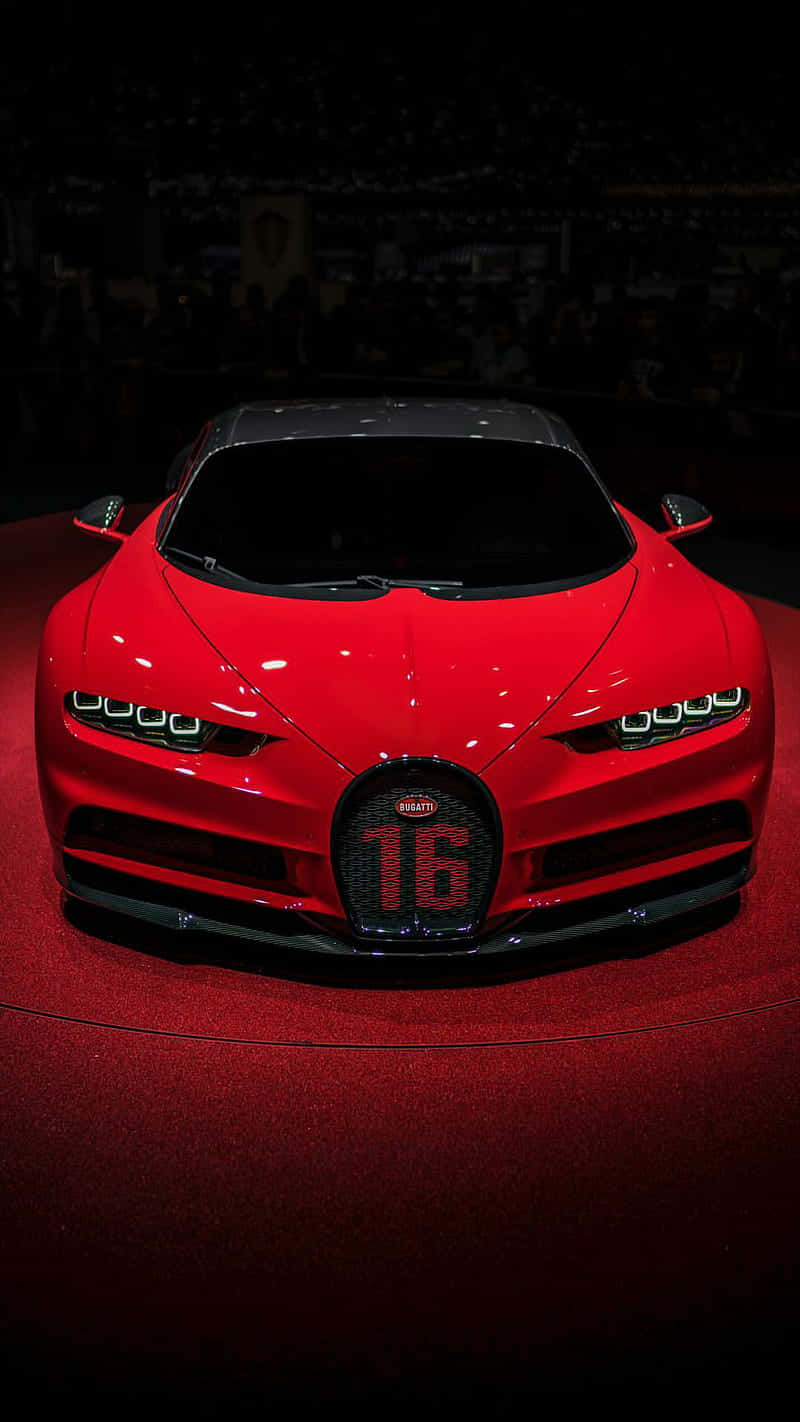 桌布 壁紙 — 一輛光亮的紅色Bugatti Chiron Super Sport 16，帶有'16'格柵徽章，在車展的紅地毯上於聚光燈下閃耀。