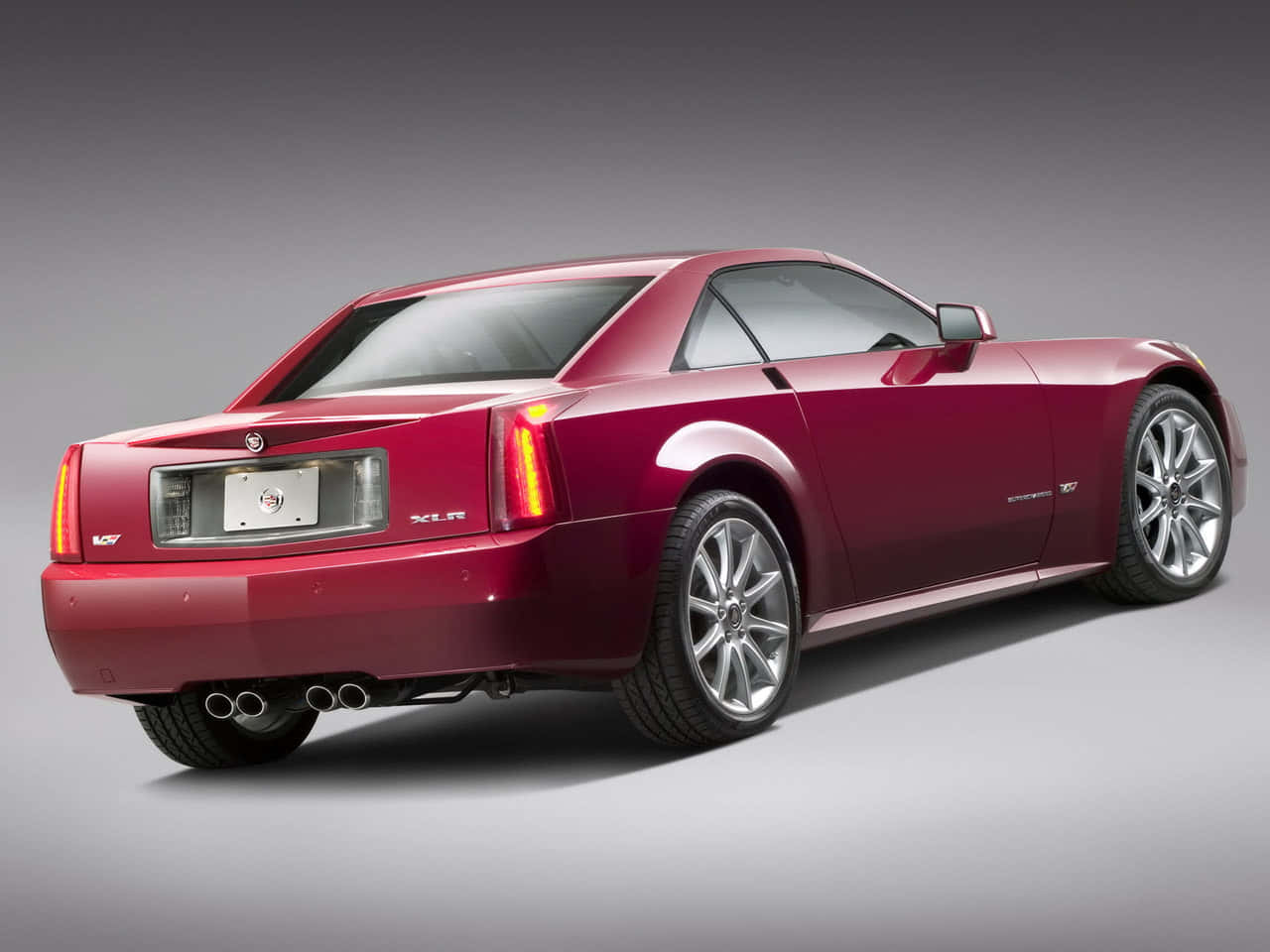 Cadillac Xlr 桌布 壁紙 — 一輛光亮的紅色Cadillac XLR跑車以四分之三後視圖展示，背景為中性灰色攝影棚。