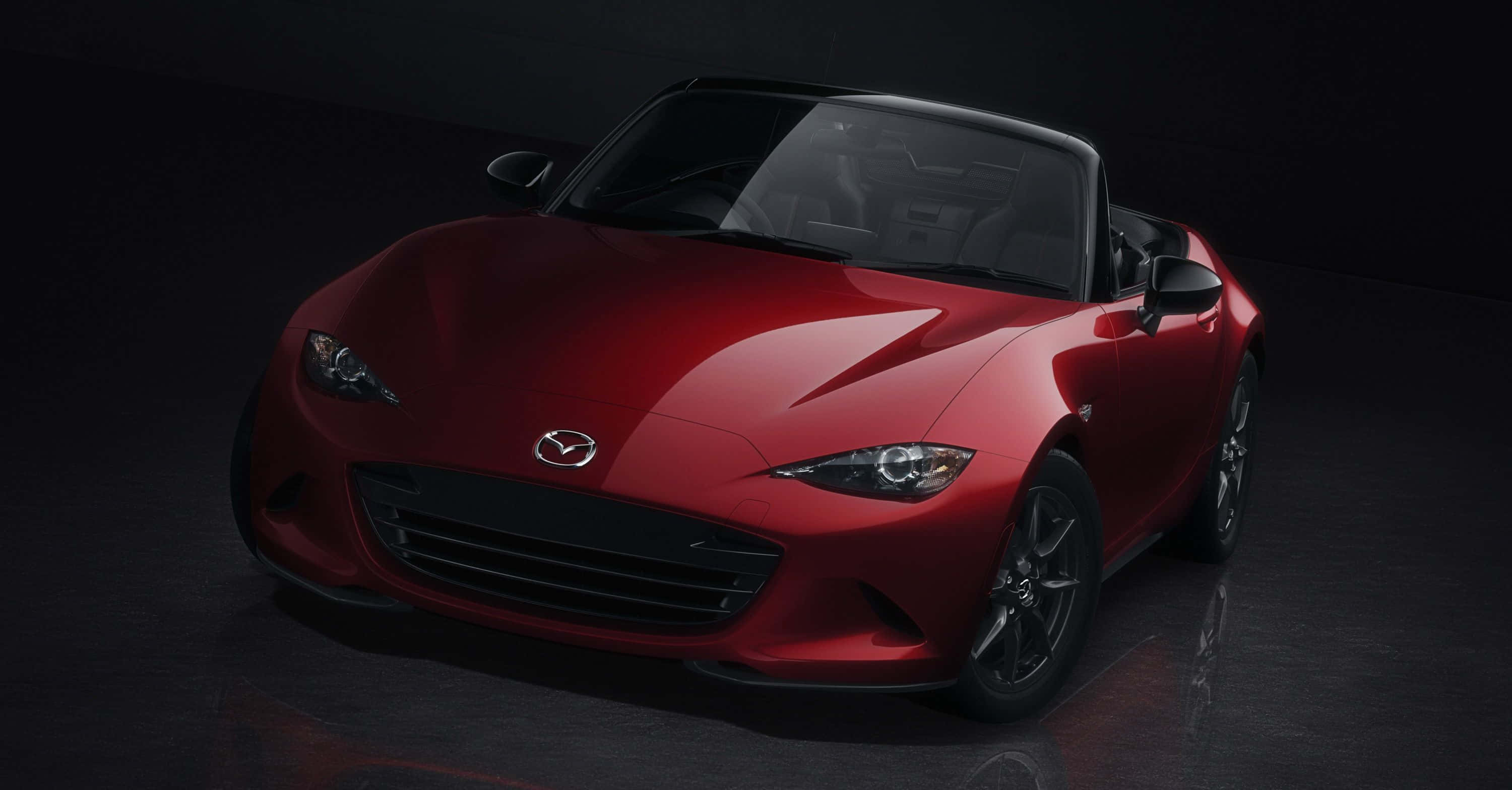桌布 壁紙 — 一輛光亮的紅色Mazda MX-5 Miata敞篷跑車在攝影棚燈光下，在深色反光地板上閃閃發光。
