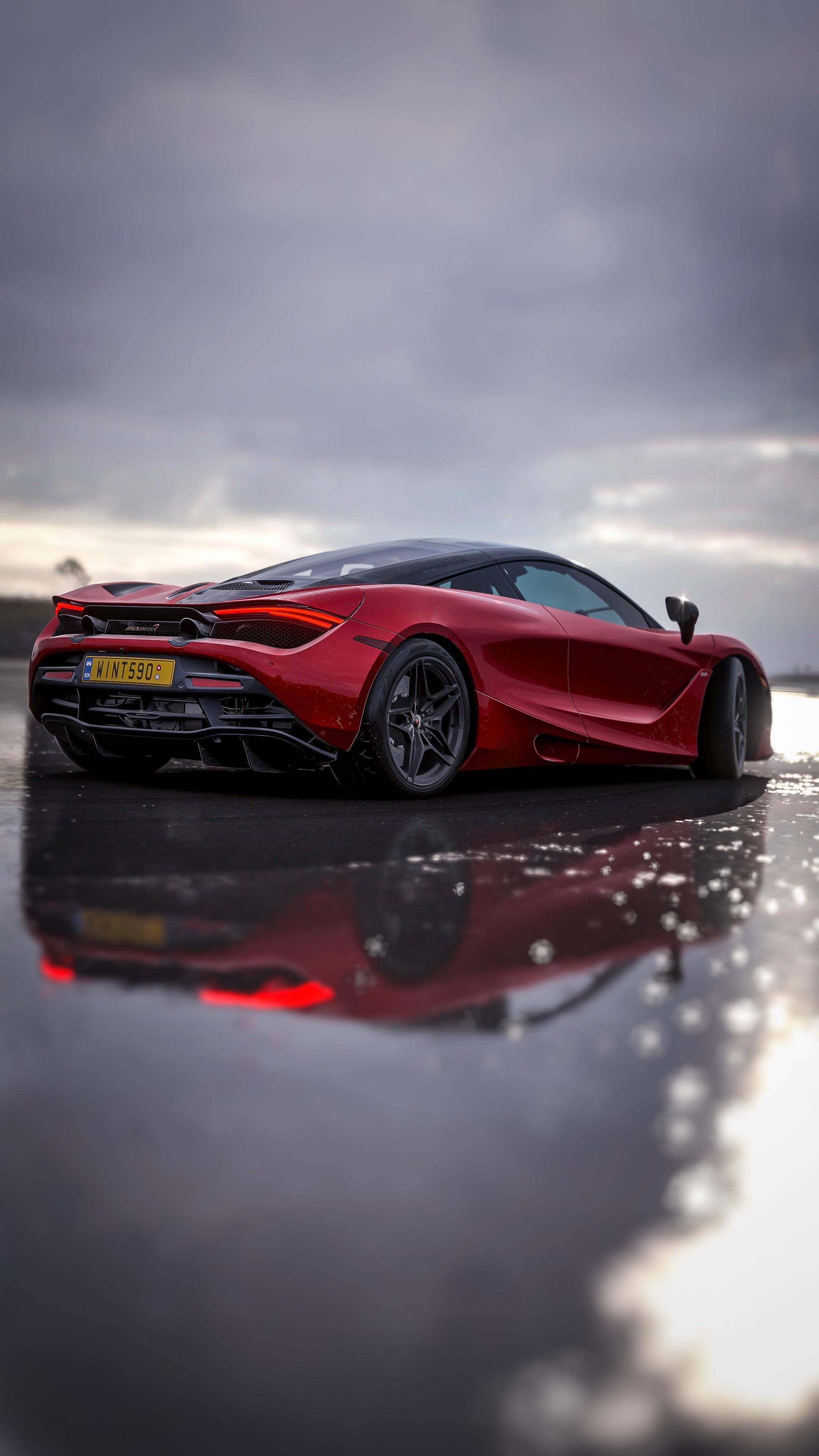 Mclaren 720s 桌布 壁紙 — 一輛光亮的紅色McLaren跑車在陰沉多雲的天空下，倒映在濕漉漉的路面上。