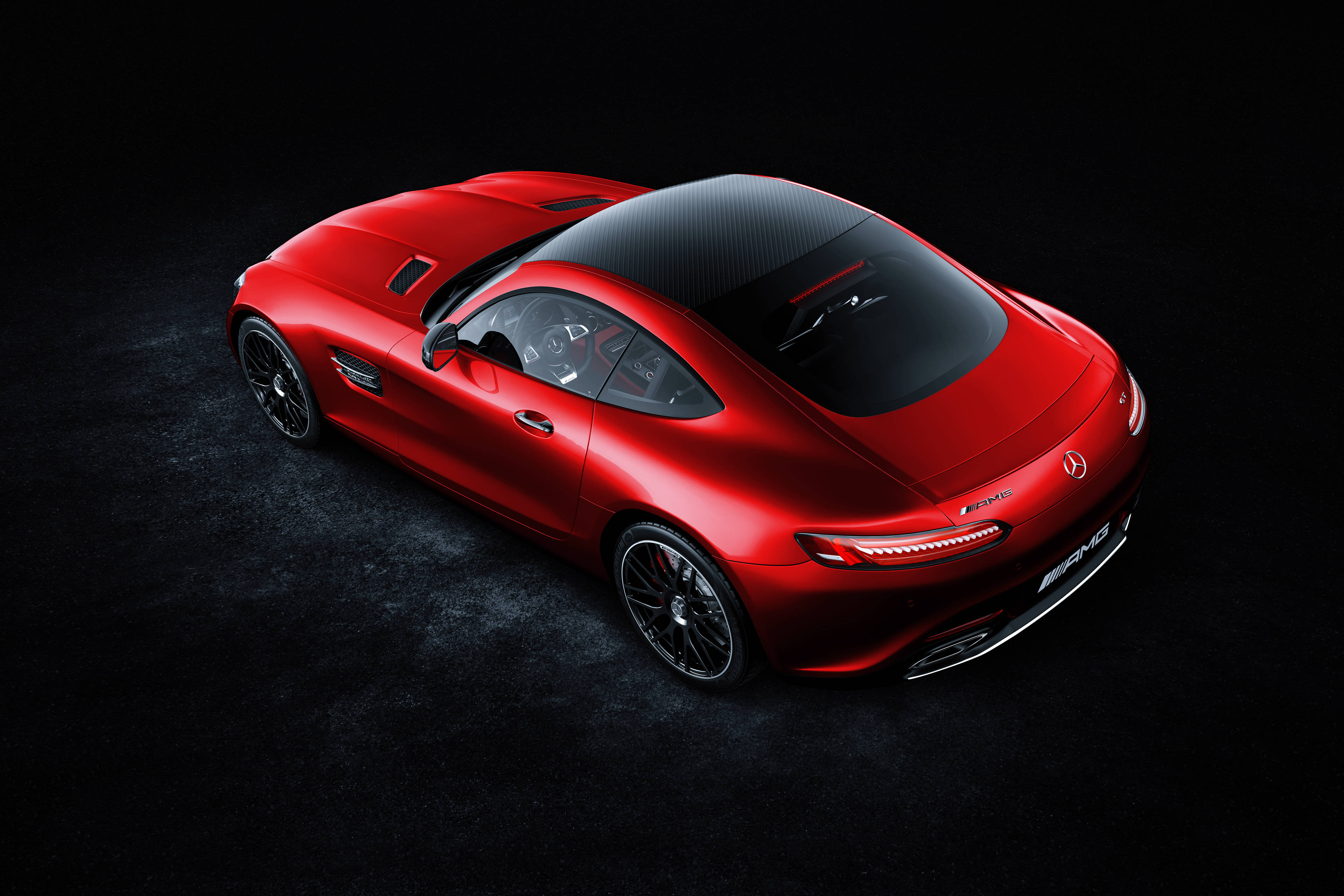 4K 奔馳壁紙 桌布 壁紙 — 一輛光亮的紅色Mercedes-AMG GT跑車配備碳纖維車頂，從高角度展示在深色紋理工作室地板上。