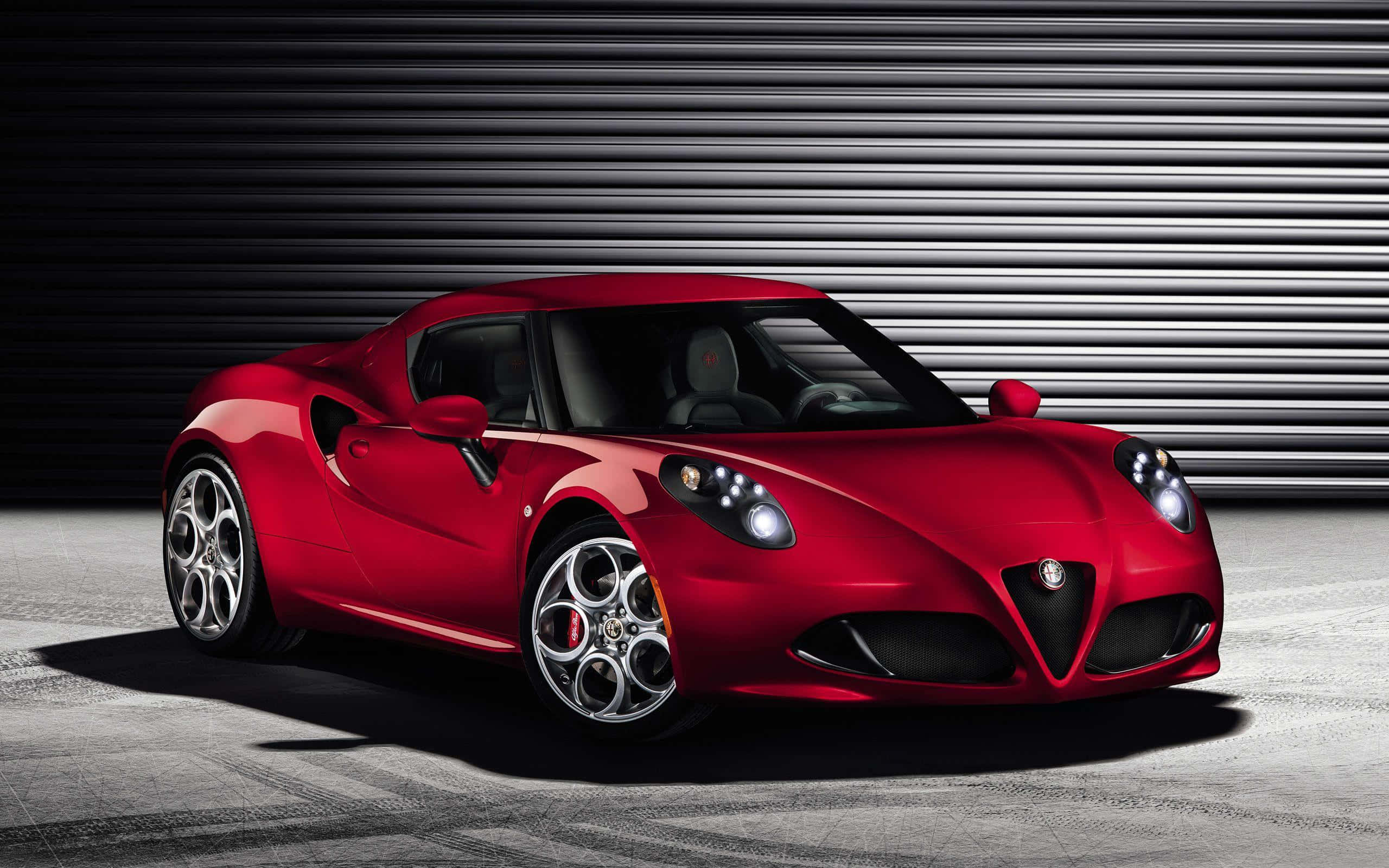 Alfa Romeo 4c 桌布 壁紙 — 一輛光亮的紅色愛快羅密歐跑車在攝影棚燈光下，以深色金屬車庫門為背景閃閃發光。