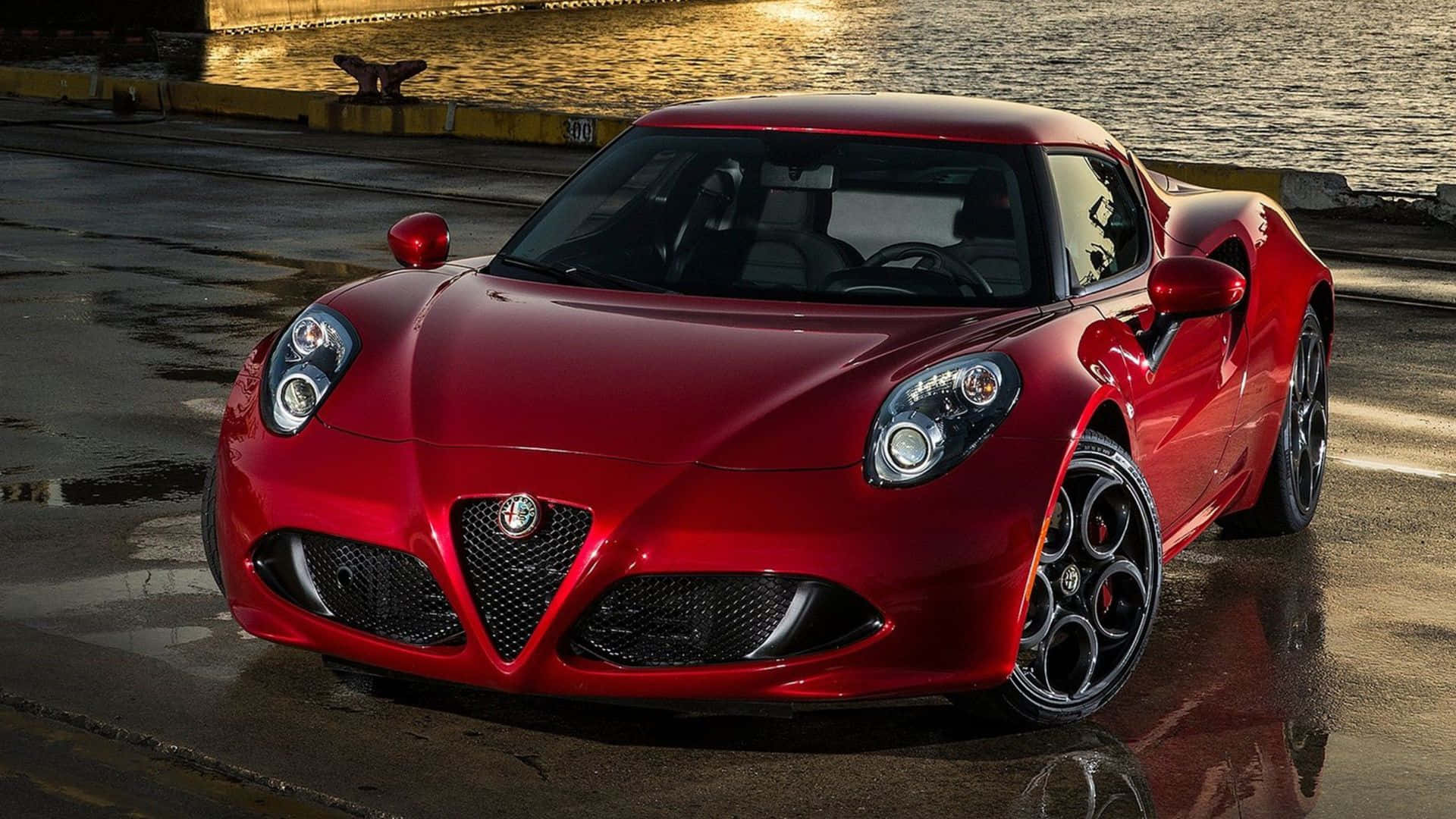 Alfa Romeo 4c 桌布 壁紙 — 一輛光亮的紅色愛快羅密歐跑車在濕滑的碼頭上閃耀，金色夕陽倒映在水面上。