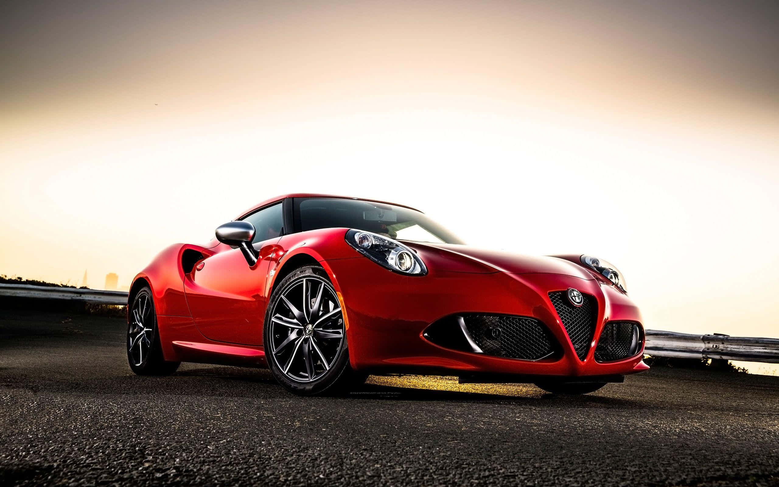 Alfa Romeo 4c 桌布 壁紙 — 一輛光亮的紅色愛快羅密歐跑車在蜿蜒的山路上，在金黃色的日落光芒下閃閃發光。