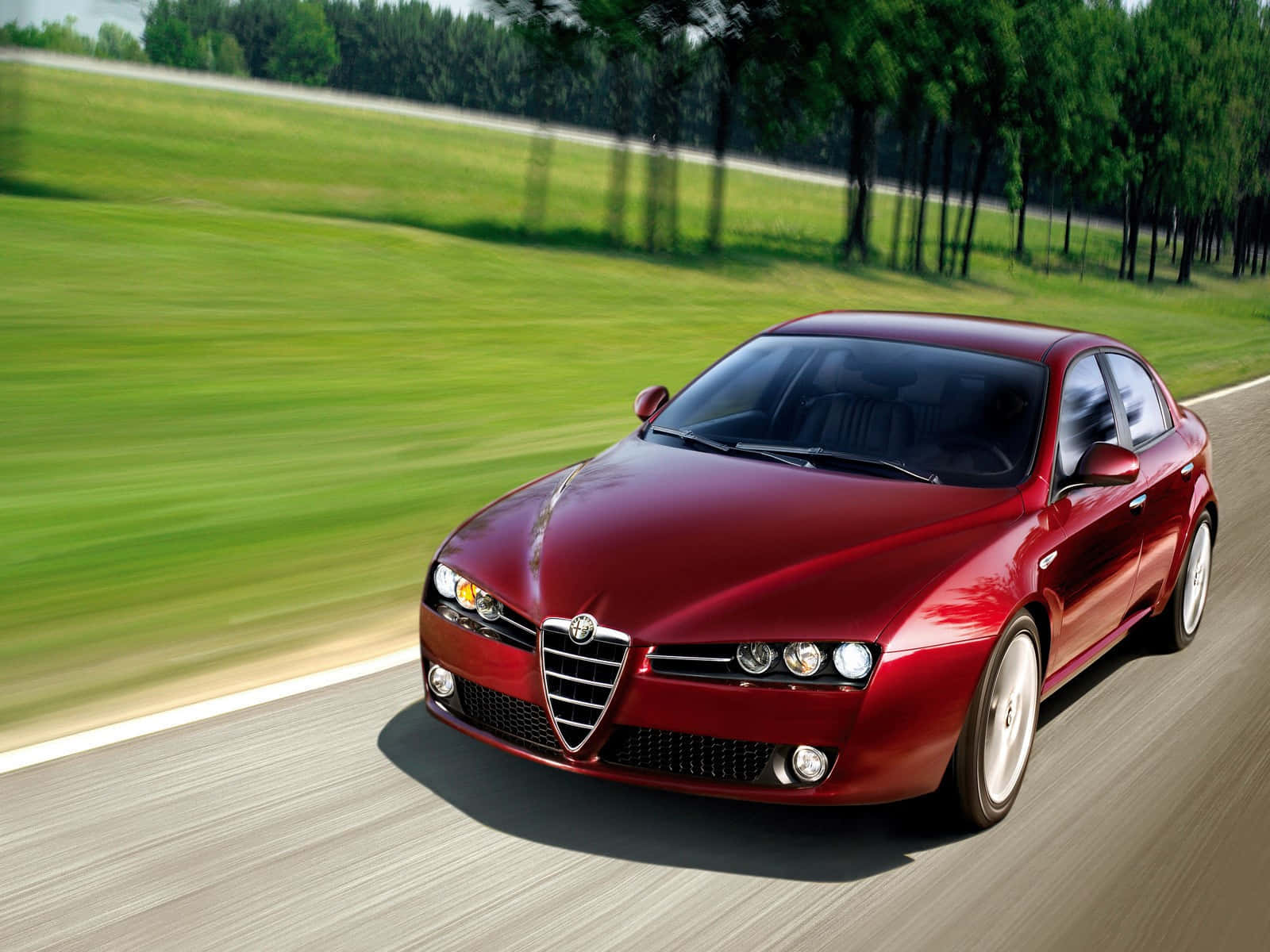 Alfa Romeo Brera 桌布 壁紙 — 一輛光亮的紅色愛快羅密歐跑車沿著蜿蜒的道路穿過翠綠的鄉村飛馳。