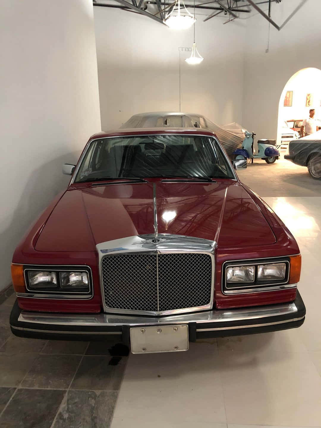 Bentley Eight 桌布 壁紙 — 一輛光亮的紅色梅賽德斯-奔馳轎車在明亮簡約的汽車展示間中正面展示，地板鋪有瓷磚，天花板橫樑外露。
