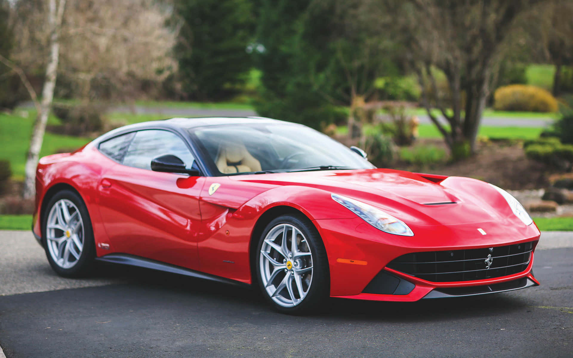 Ferrari F12 Berlinetta 桌布 壁紙 — 一輛光亮的紅色法拉利F12tdf跑車停在柏油路上，背景有綠樹和灌木。