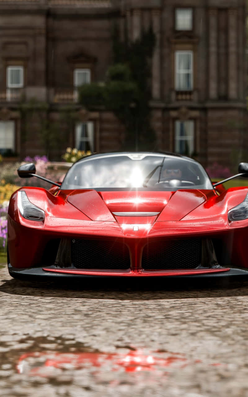 Android Forza Horizon 4 桌布 壁紙 — 一輛光亮的紅色法拉利LaFerrari跑車在宏偉石砌豪宅前的濕滑鵝卵石車道上閃閃發光。