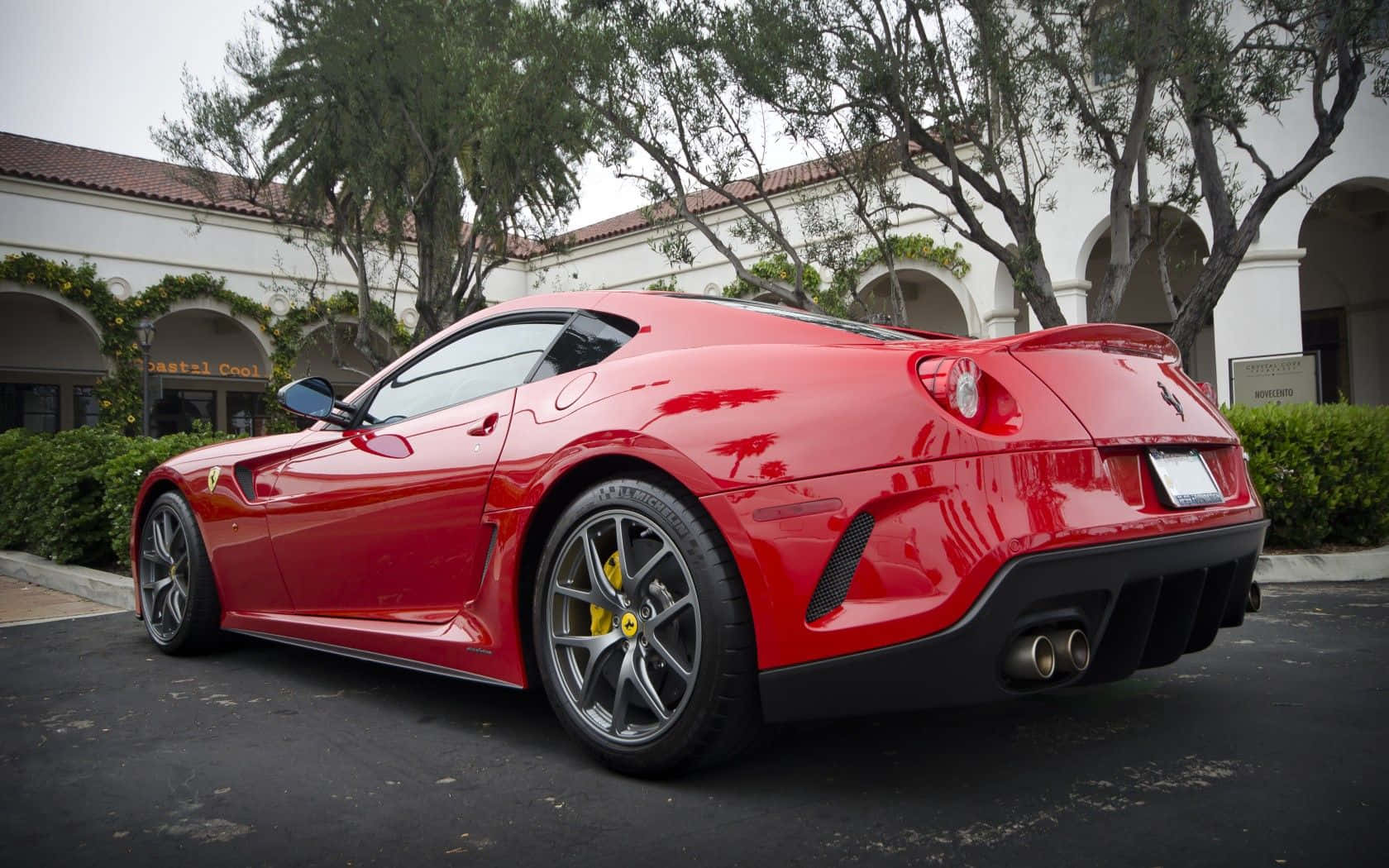 Ferrari 599 Gtb Fiorano 桌布 壁紙 — 一輛光亮的紅色法拉利跑車停放在戶外樹下，背景是一座白色建築。