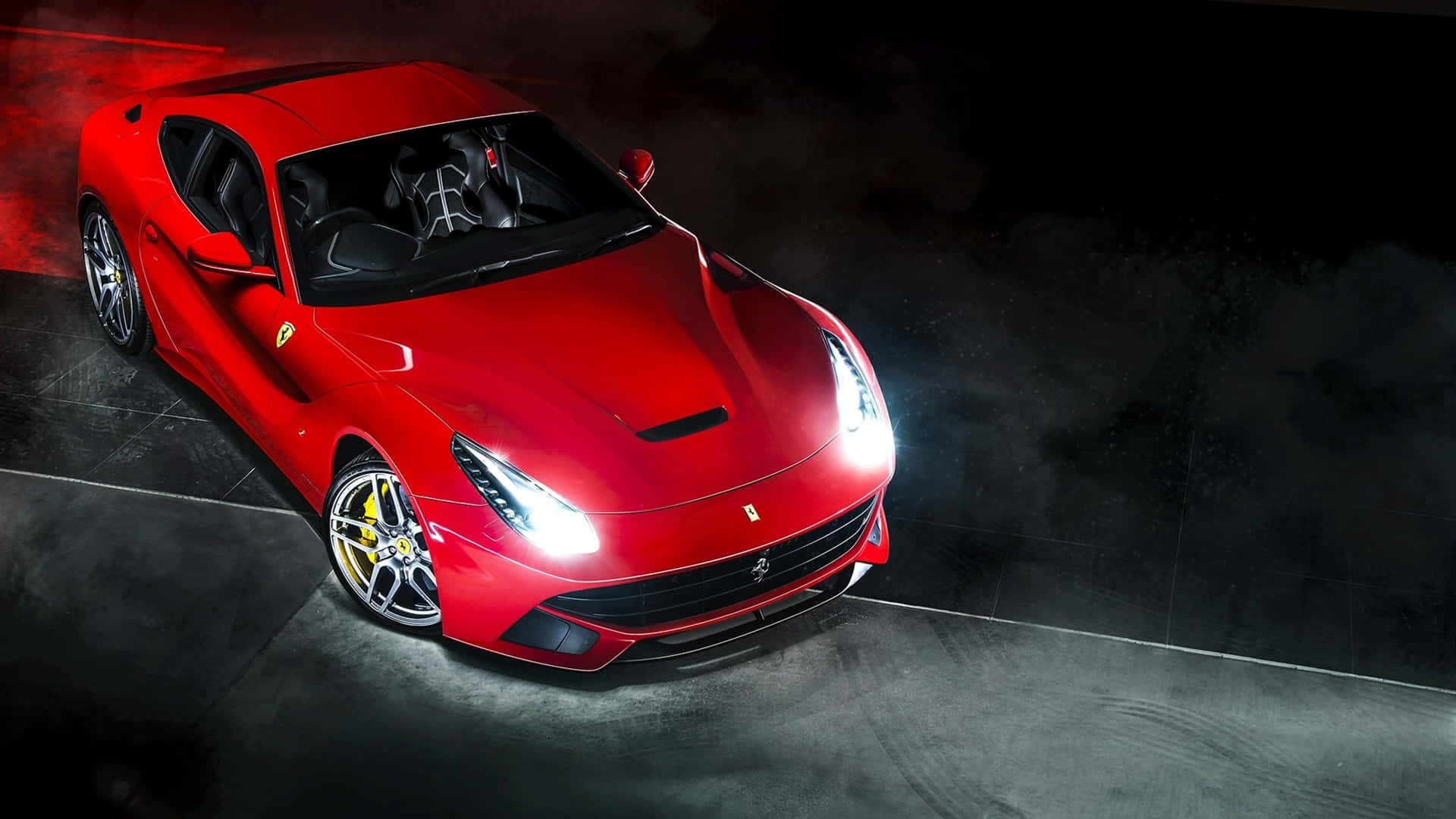 Ferrari F12 Berlinetta 桌布 壁紙 — 一輛光亮的紅色法拉利跑車在戲劇性的攝影棚燈光下閃耀，背景是黑暗煙霧繚繞。